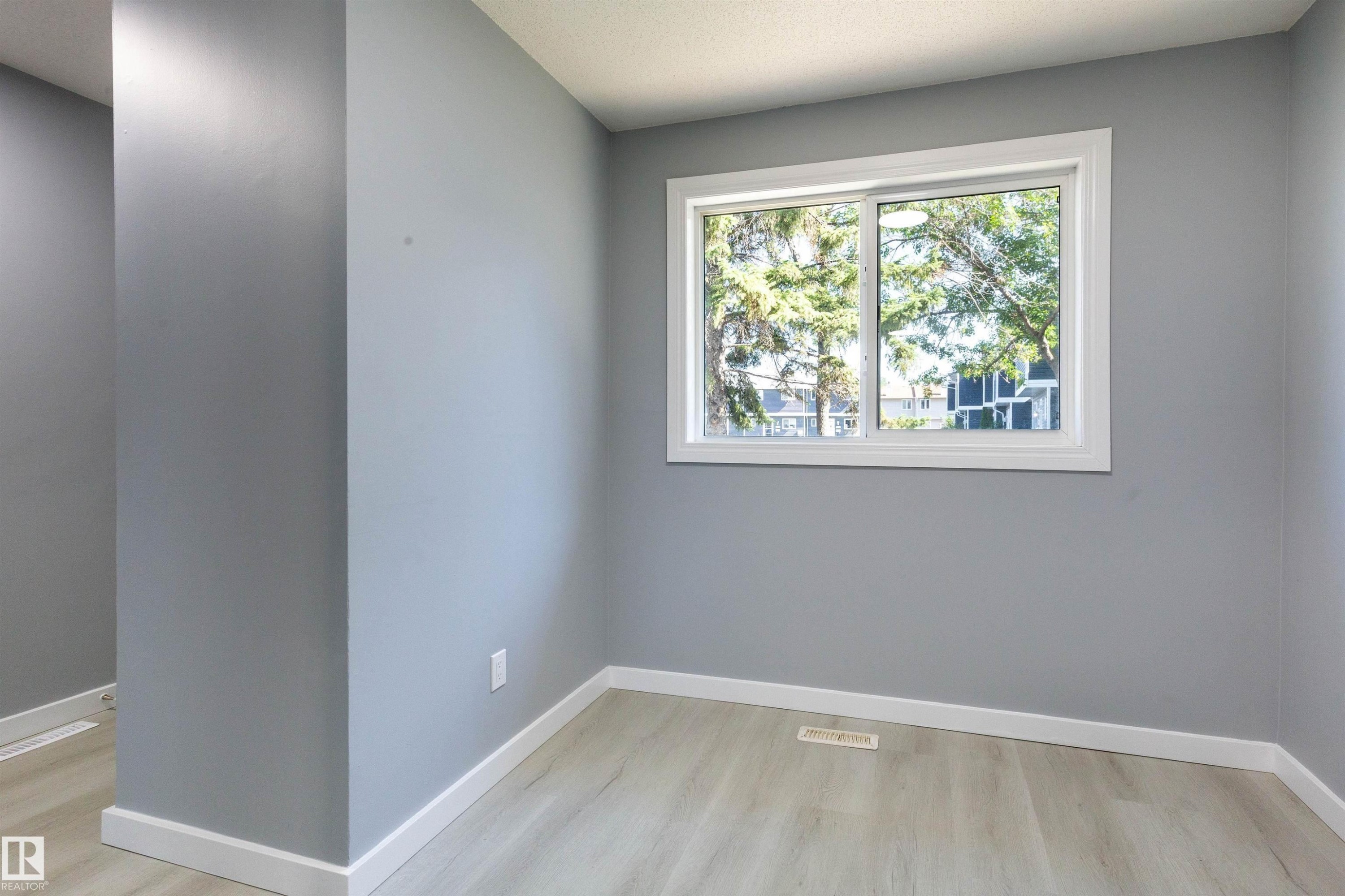 Room featuring a white-framed window, light gray walls, white baseboards, and wood-finish flooring - 547 Dunluce Road, Edmonton, AB - Indoor Photo Showing Other Room