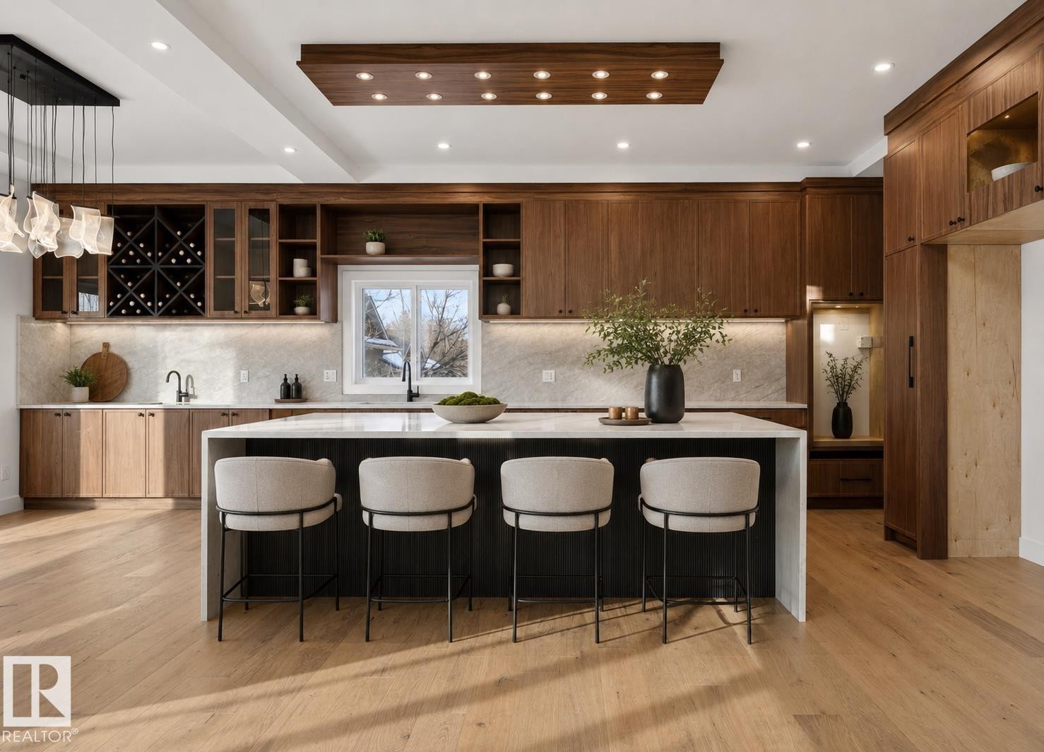Gourmet kitchen featuring a waterfall island with integrated seating, extensive wood-finish cabinetry, a built-in wine rack, light wood-finish flooring, and a recessed ceiling panel with integrated lighting - 5820 110 Street, Edmonton, AB - Indoor Photo Showing Kitchen With Upgraded Kitchen