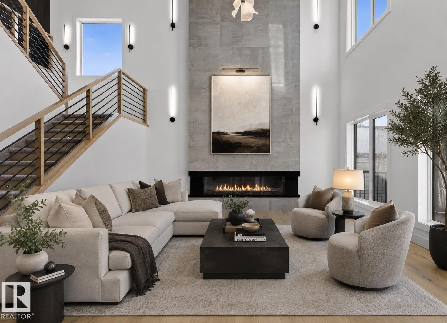 Two-story living area featuring a linear fireplace with a textured surround, light wood-finish flooring, and a staircase with natural wood handrails and black metal balusters - 5820 110 Street, Edmonton, AB - Indoor Photo Showing Living Room With Fireplace