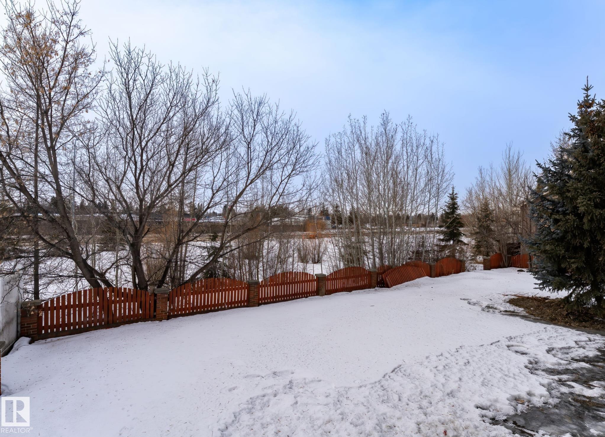 Expansive yard featuring a red picket fence, mature trees, and evergreen landscaping - 5820 110 Street, Edmonton, AB - Outdoor