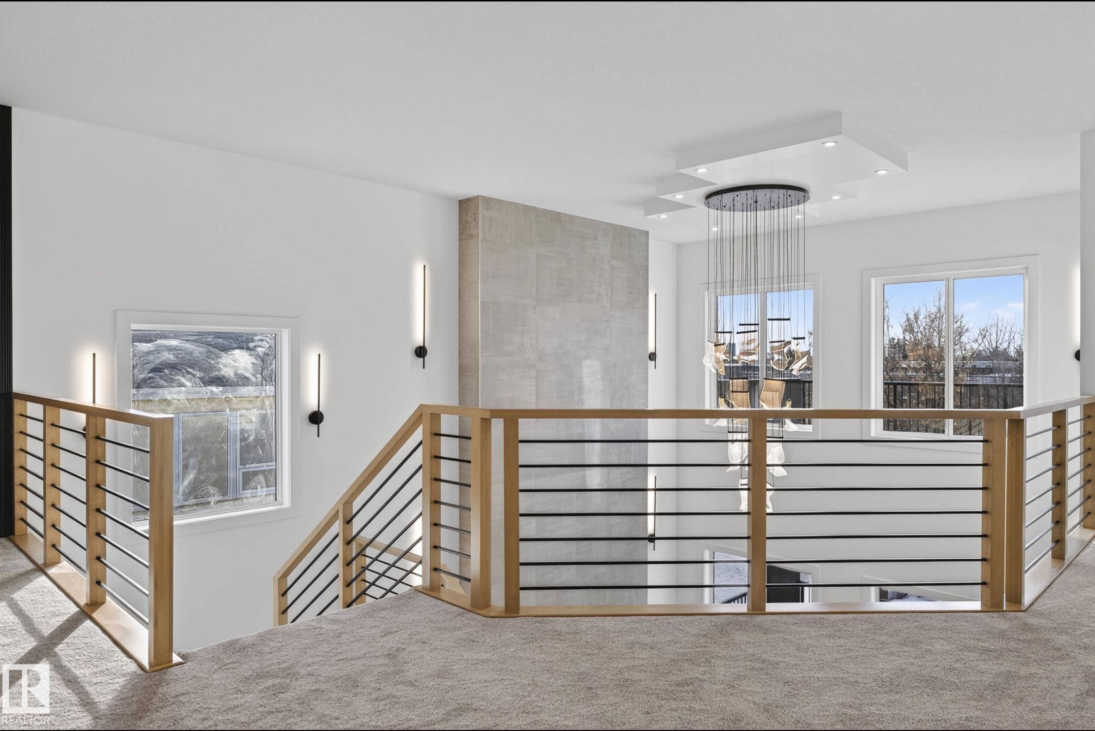 Open-concept upper-level featuring light wood and black metal railings, a textured accent wall, recessed lighting, and a multi-tiered chandelier - 5820 110 Street, Edmonton, AB - Indoor Photo Showing Other Room