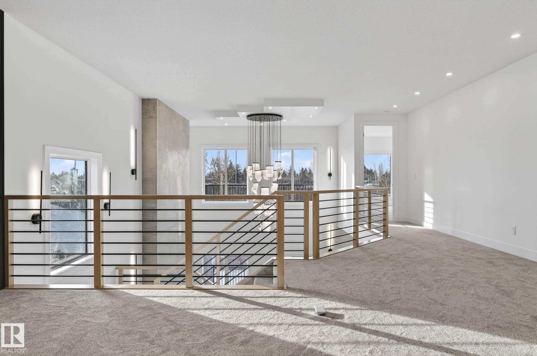 Upper-level landing featuring a contemporary chandelier, recessed lighting, and a horizontal bar railing with wood newel posts - 5820 110 Street, Edmonton, AB - Indoor Photo Showing Other Room
