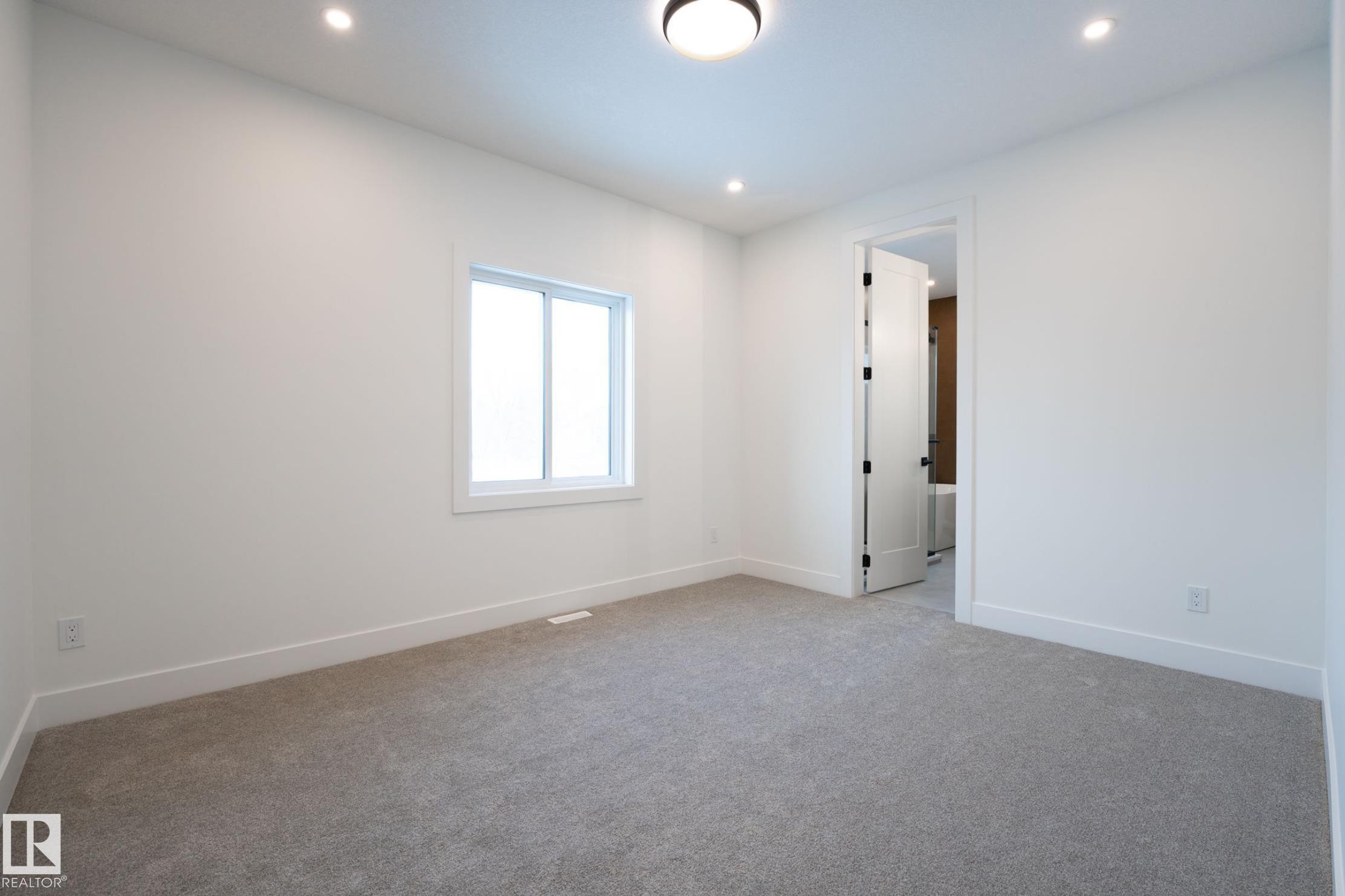 Carpeted room featuring white walls, bright window, recessed lighting, and a white interior door with black hardware - 5820 110 Street, Edmonton, AB - Indoor Photo Showing Other Room