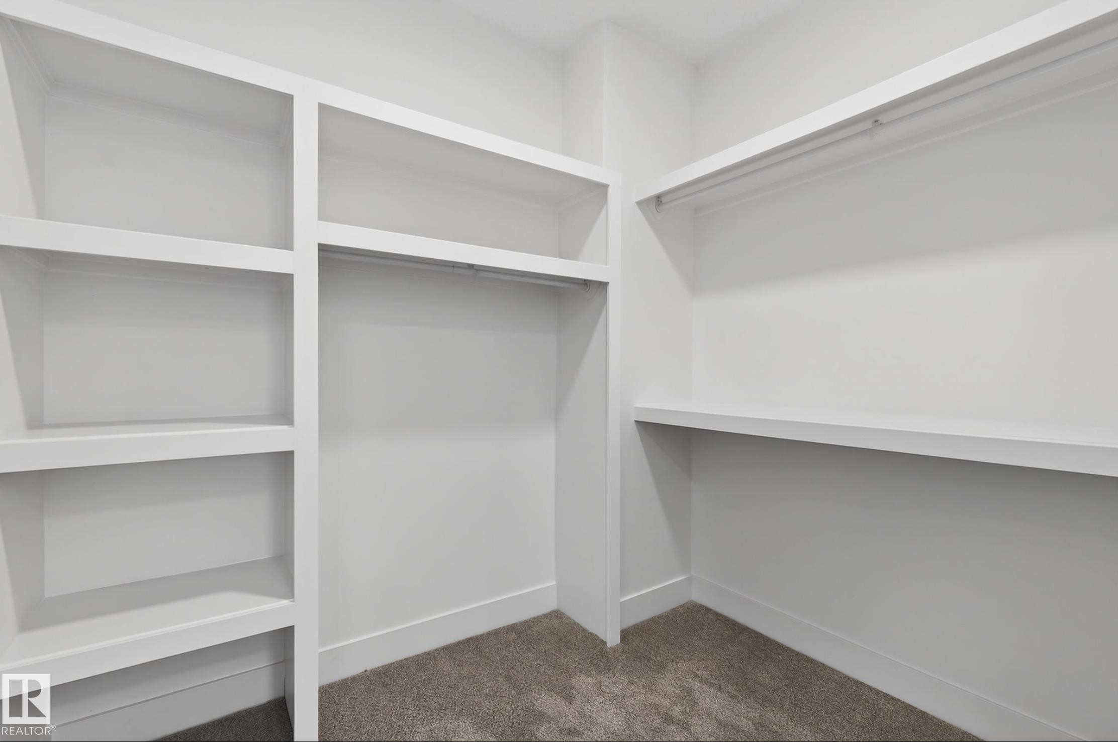 Custom storage system featuring white shelving units, integrated hanging rods, and neutral-toned carpeting - 5820 110 Street, Edmonton, AB - Indoor With Storage