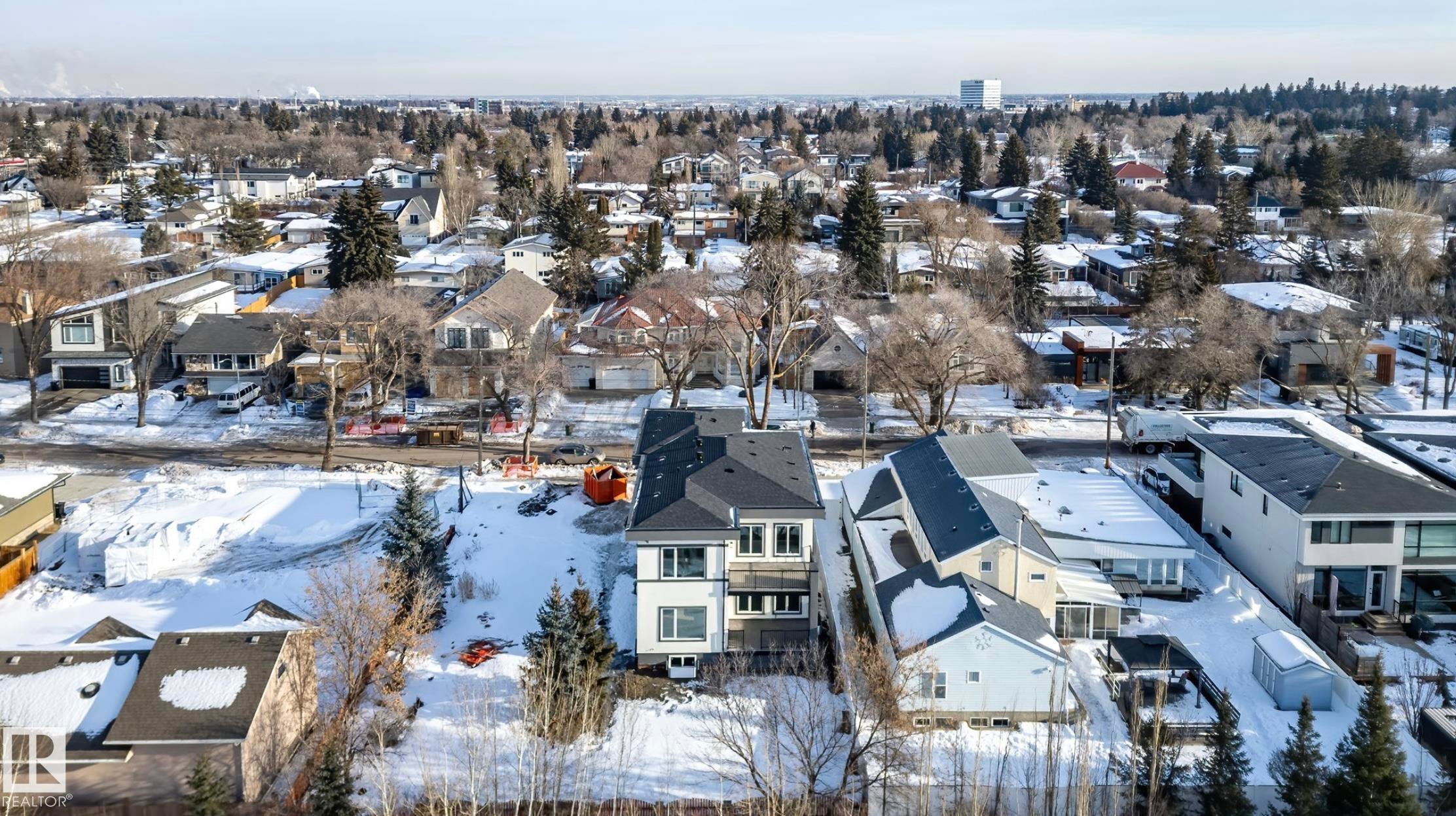 Modern multi-story property with a dark-pitched roof and light-colored siding, situated in a residential area featuring established tree cover - 5820 110 Street, Edmonton, AB - Outdoor With View