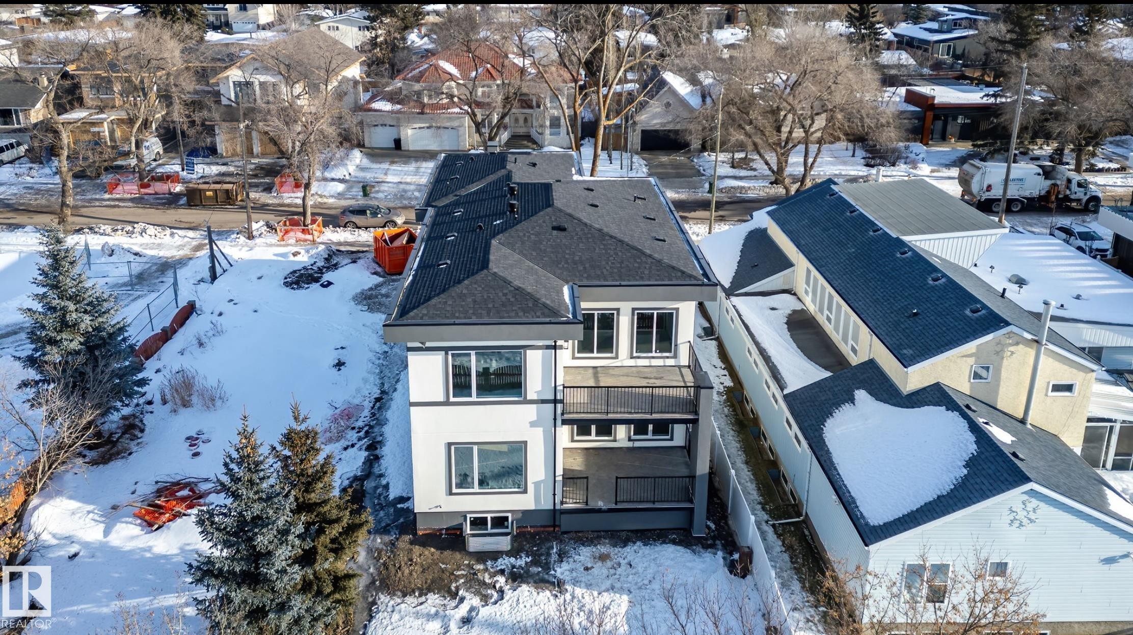 Contemporary two-story exterior featuring white siding with dark trim, multiple large windows, a second-story balcony with dark railings, and a dark shingle roof - 5820 110 Street, Edmonton, AB - Outdoor