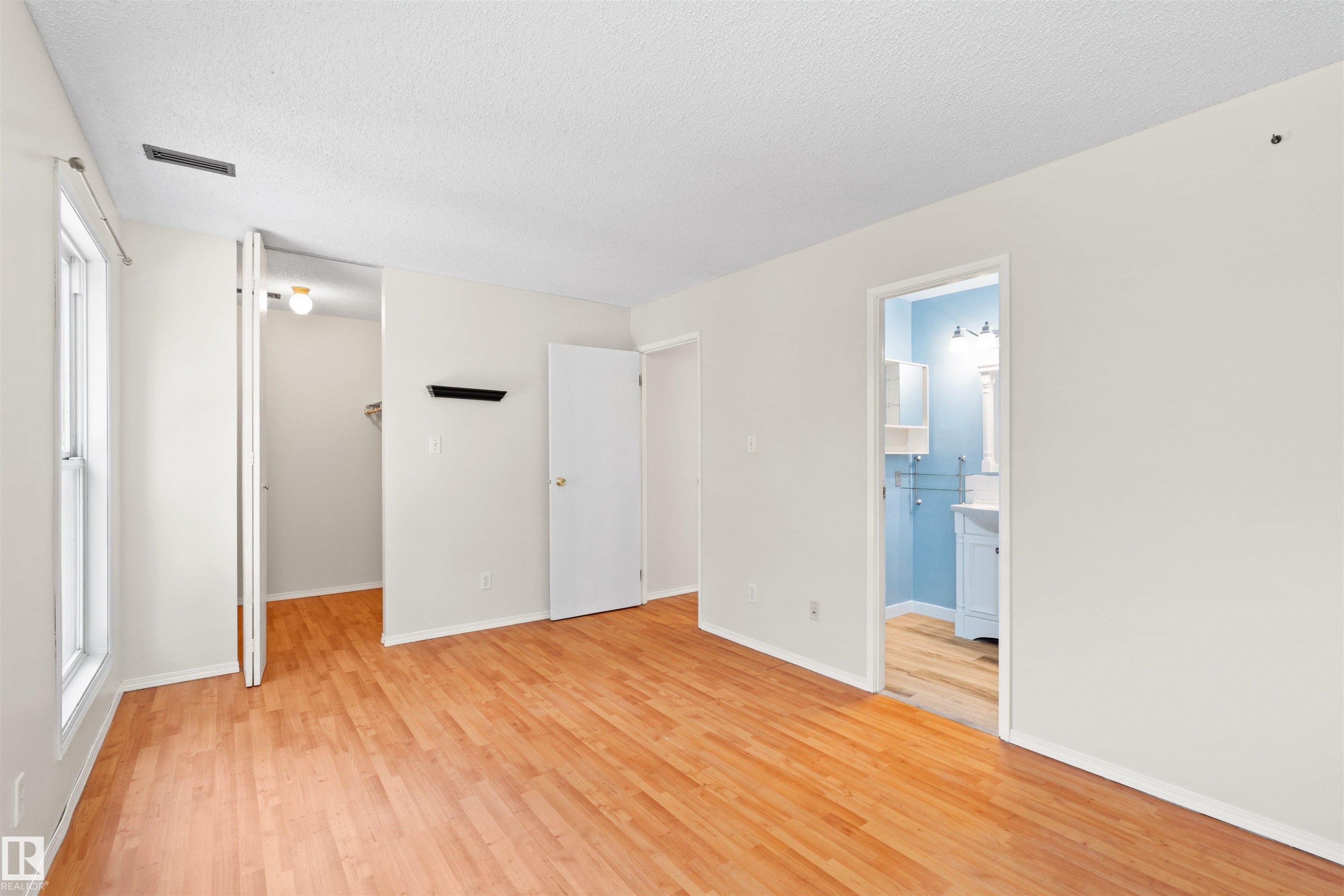 Bright interior space featuring wood-finish flooring, white walls, and a textured ceiling - 1116 Saddleback Road, Edmonton, AB - Indoor Photo Showing Other Room