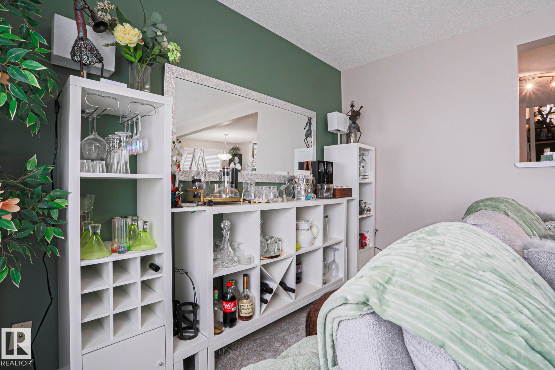 Built-in shelving unit featuring wine storage, stemware racks, and a mirrored accent wall - 1621 64 Street, Edmonton, AB - Indoor Photo Showing Bedroom