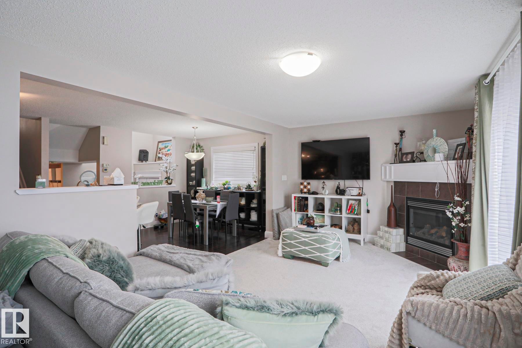 Carpeted living area featuring a built-in fireplace with a tile surround and a mantel - 1621 64 Street, Edmonton, AB - Indoor Photo Showing Living Room With Fireplace