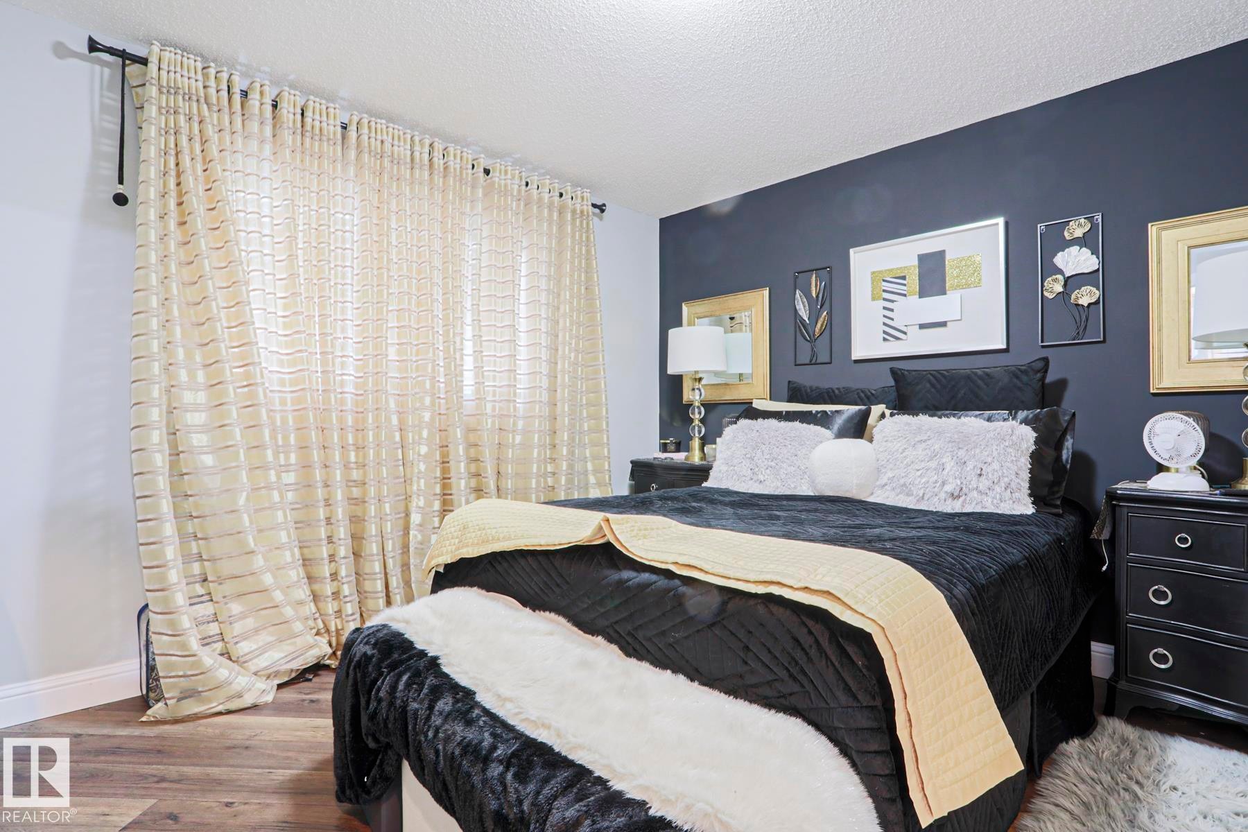Bedroom featuring a prominent accent wall, wood-finish flooring, and crown molding - 1621 64 Street, Edmonton, AB - Indoor Photo Showing Bedroom