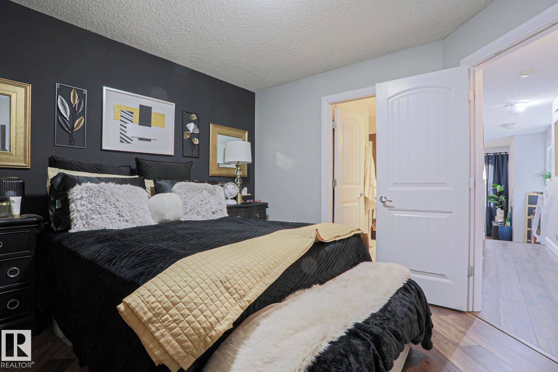 Bedroom featuring a dark accent wall, light grey painted walls, wood-finish flooring, and white interior doors - 1621 64 Street, Edmonton, AB - Indoor Photo Showing Bedroom