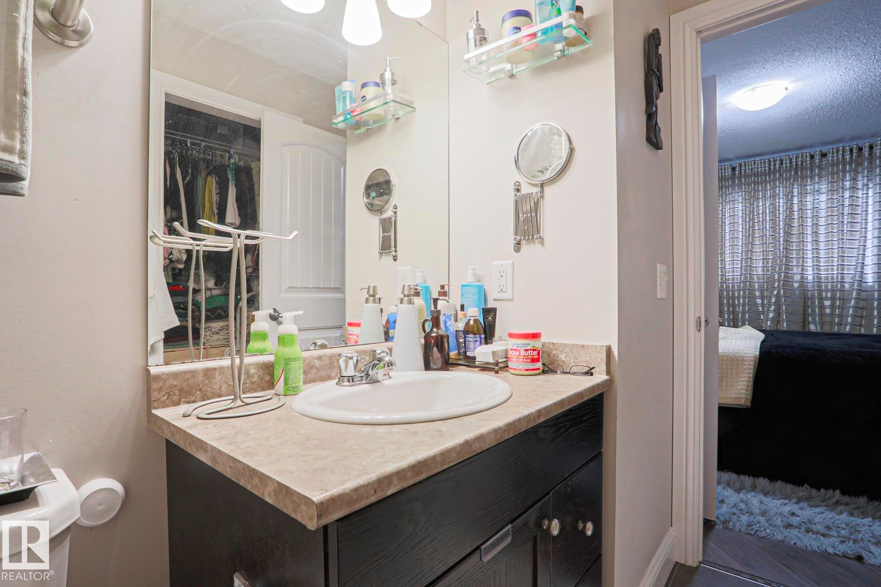 Bathroom vanity featuring a single basin, laminate countertop, and dark wood-finish cabinetry - 1621 64 Street, Edmonton, AB - Indoor Photo Showing Bathroom