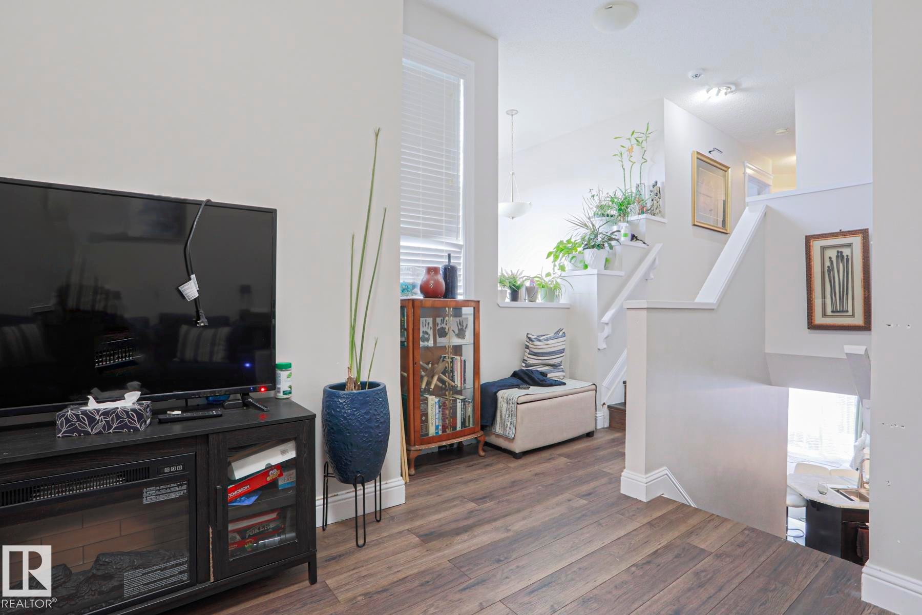 Wood-finish flooring throughout, featuring a staircase with white risers and handrails, an upper landing with natural light, and a built-in display cabinet - 1621 64 Street, Edmonton, AB - Indoor Photo Showing Other Room