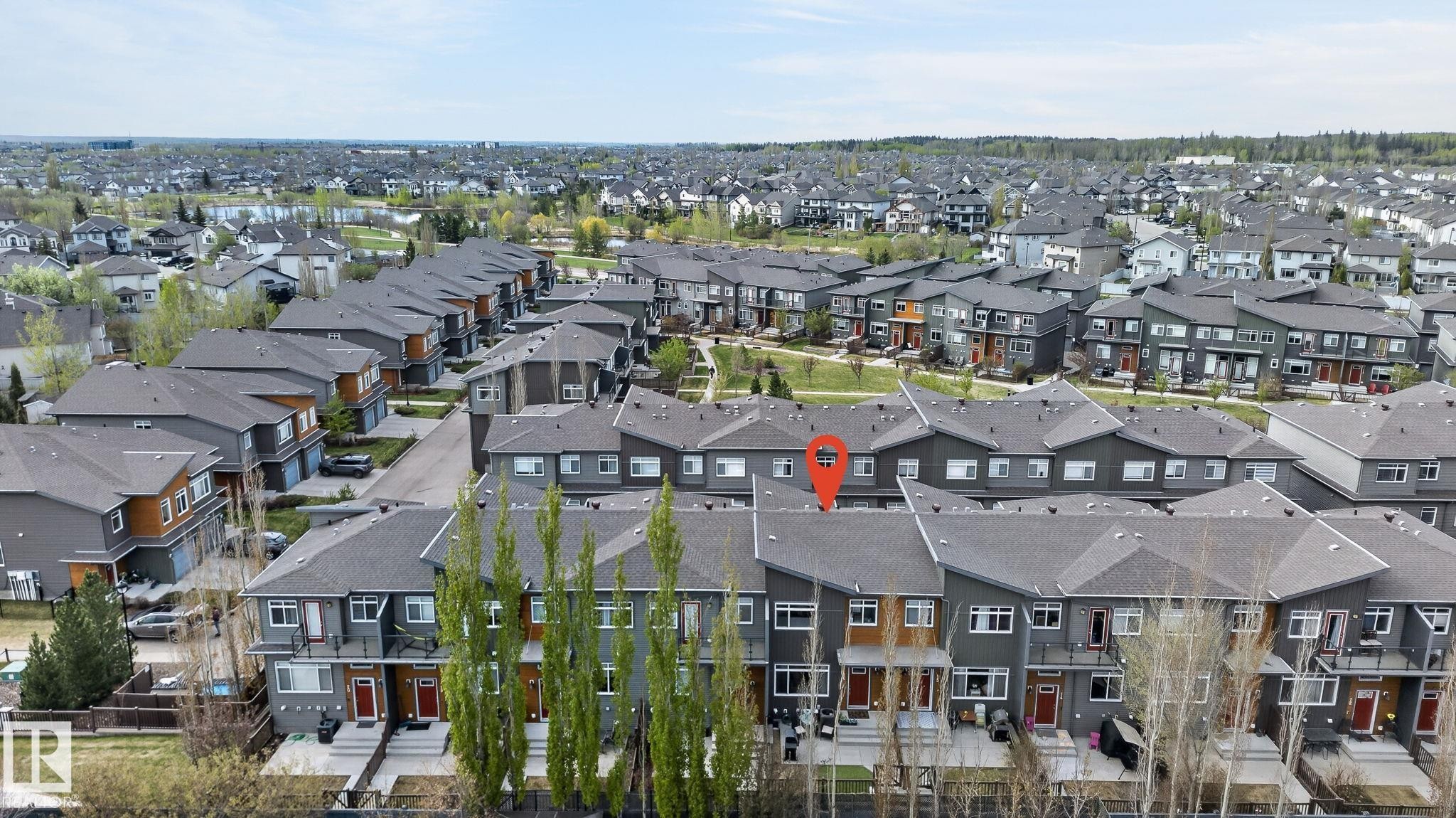 Contemporary townhome with a dark gray exterior, light wood-tone accents, and a contrasting red entry door - 16 7503 Getty Gate, Edmonton, AB - Outdoor