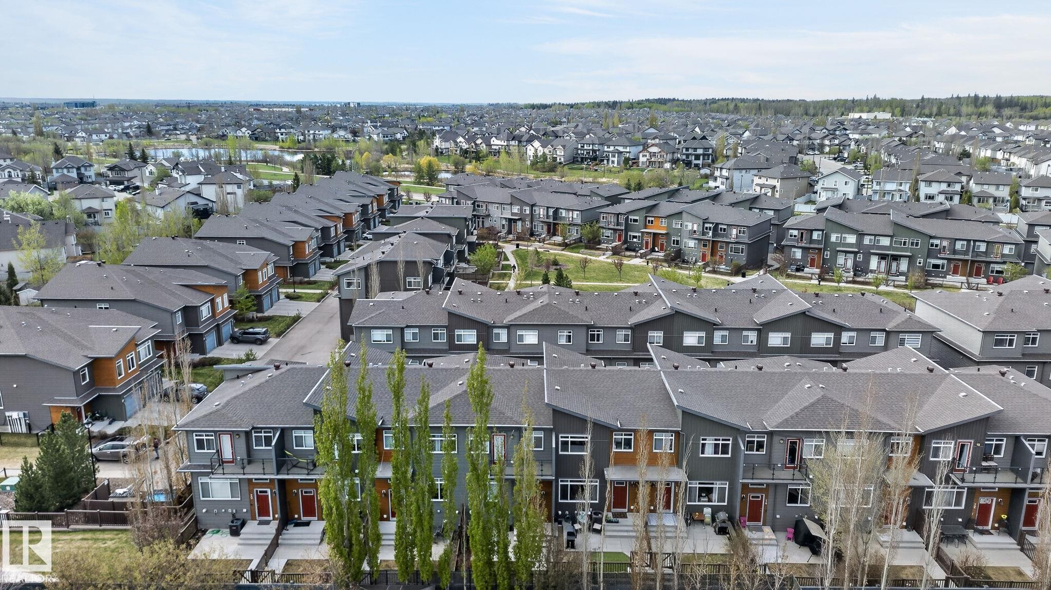 Contemporary townhomes featuring grey siding with wood-tone accents and dark shingle roofs - 16 7503 Getty Gate, Edmonton, AB - Outdoor