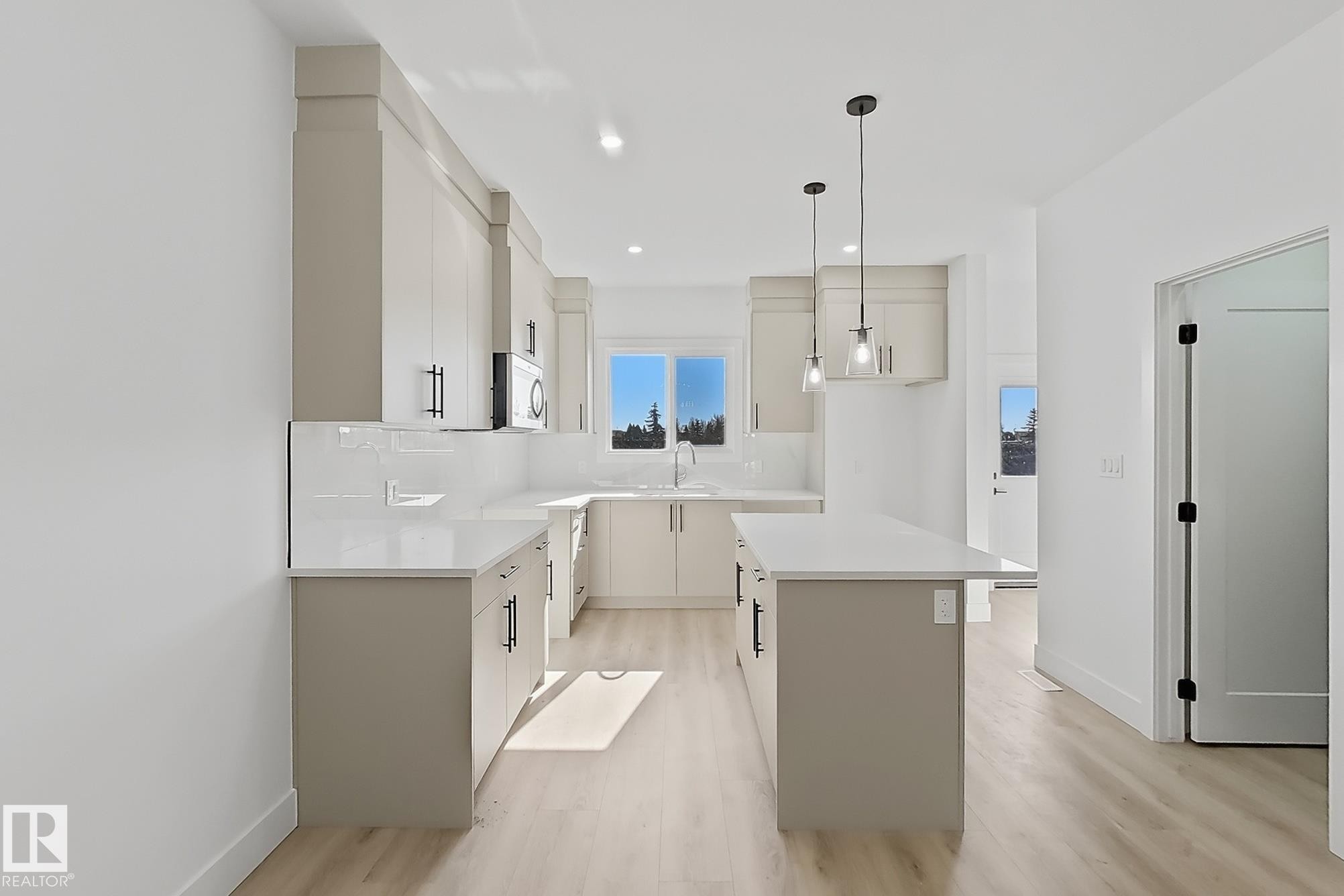 Contemporary kitchen featuring light-toned cabinetry with black hardware, white countertops, and a white subway tile backsplash - 4215 63 St, Beaumont, AB - Indoor Photo Showing Kitchen With Upgraded Kitchen