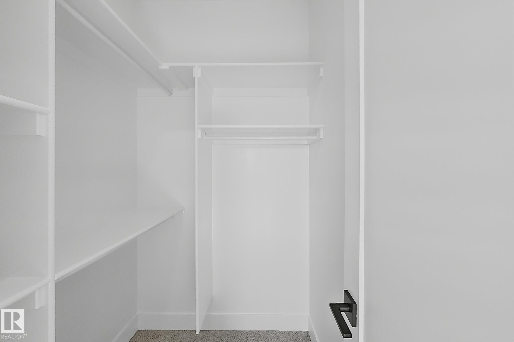 Integrated closet shelving system featuring multiple storage levels and hanging rods - 4215 63 St, Beaumont, AB - Indoor With Storage