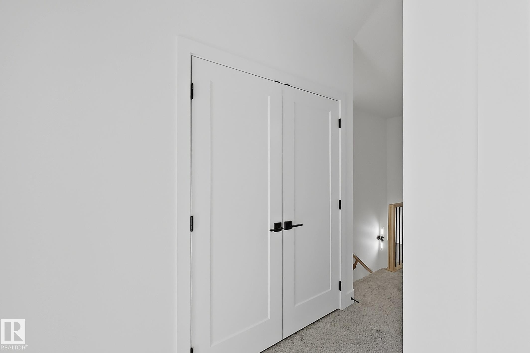White paneled bifold doors featuring matte black hardware, white trim, and light gray carpet - 4215 63 St, Beaumont, AB - Indoor Photo Showing Other Room