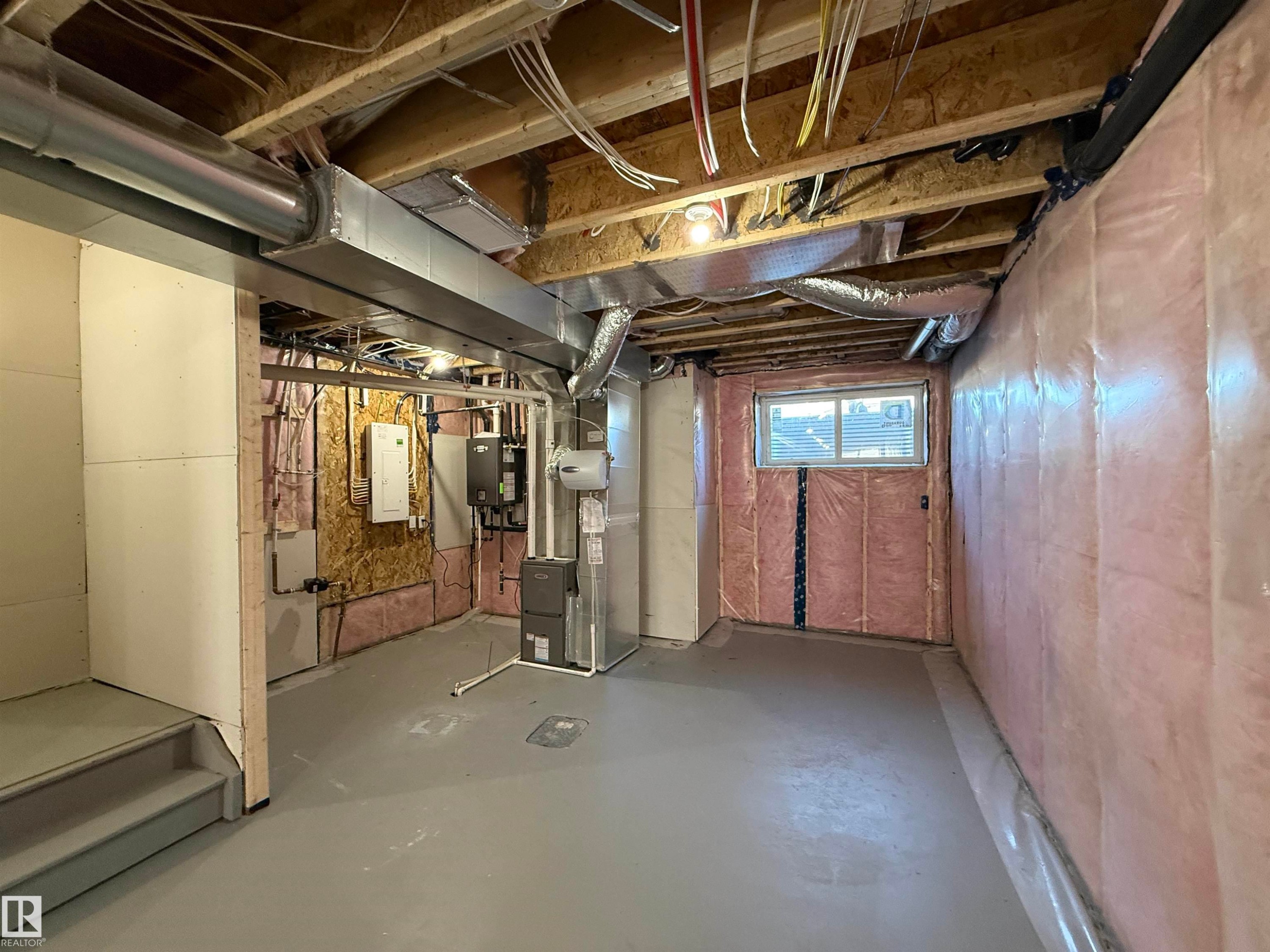 Unfinished basement space featuring visible insulation, exposed ceiling joists, utility systems, and a window - 4215 63 St, Beaumont, AB - Indoor Photo Showing Basement
