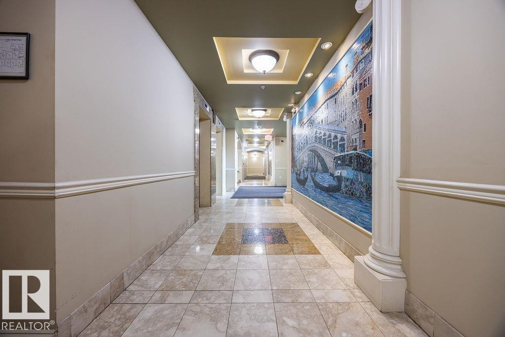 Hallway featuring a decorative mosaic wall art, recessed lighting, and a coffered ceiling with flush mount fixtures - #214 10333 112 St Nw, Edmonton, AB - Indoor Photo Showing Other Room