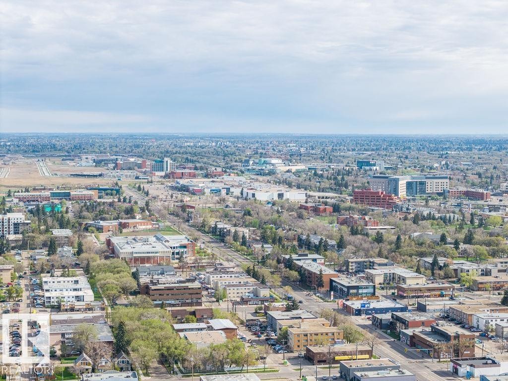 Expansive aerial perspective showcasing a developed urban landscape with diverse architectural styles, mature trees, and visible infrastructure including roads and buildings - #214 10333 112 St Nw, Edmonton, AB - Outdoor With View