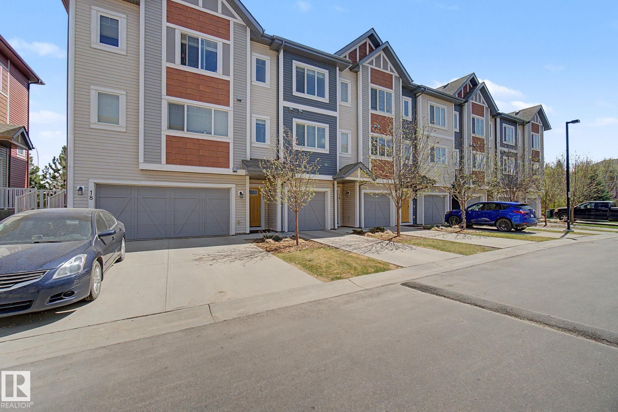 Contemporary townhome exterior featuring multi-level architecture with distinct siding patterns and colors, individual garage entrances, private driveways, and covered front entryways - 17 320 Secord Boulevard, Edmonton, AB - Outdoor With Facade