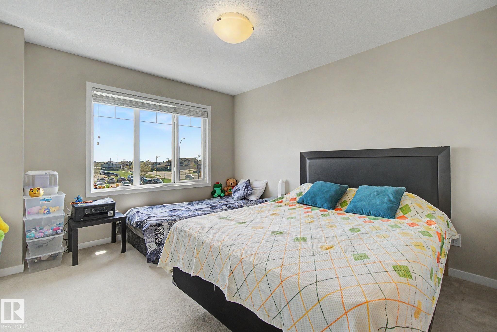 Bright bedroom featuring light-toned walls and plush carpet flooring - 17 320 Secord Boulevard, Edmonton, AB - Indoor Photo Showing Bedroom