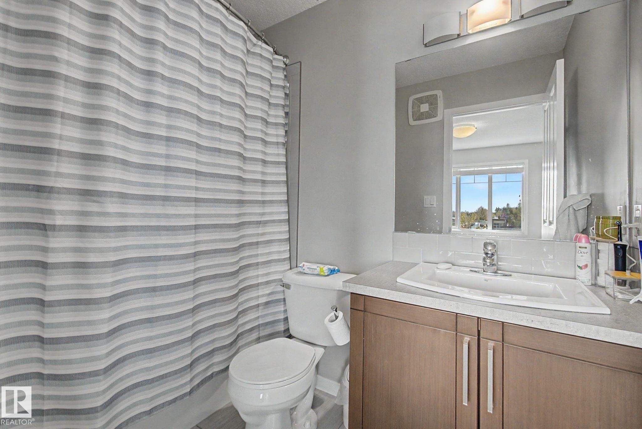Bathroom vanity featuring wood-finish cabinetry, a rectangular undermount sink, and a laminate countertop - 17 320 Secord Boulevard, Edmonton, AB - Indoor Photo Showing Bathroom