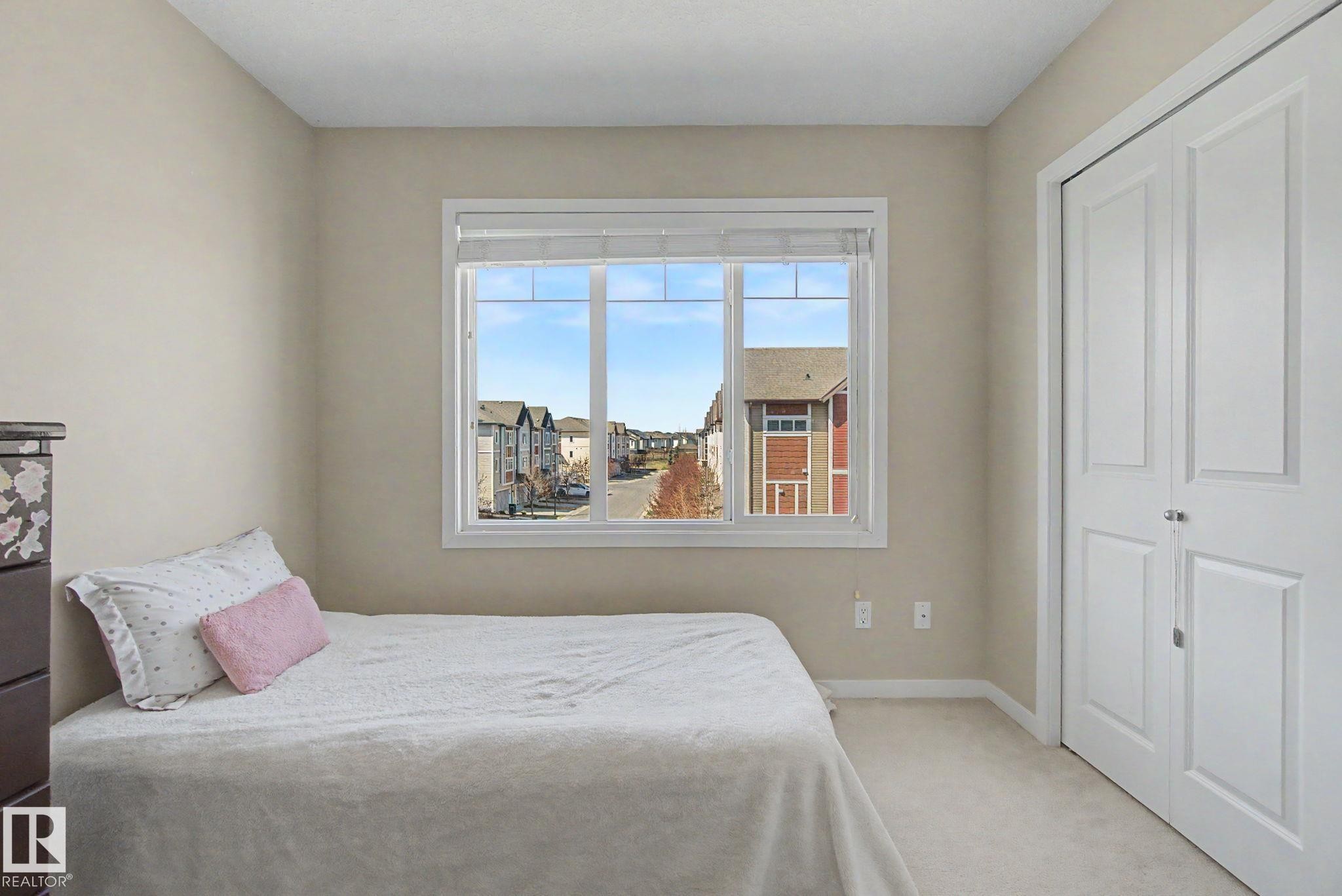 Neutral-toned walls and plush carpeting complement the natural light from the window - 17 320 Secord Boulevard, Edmonton, AB - Indoor Photo Showing Bedroom