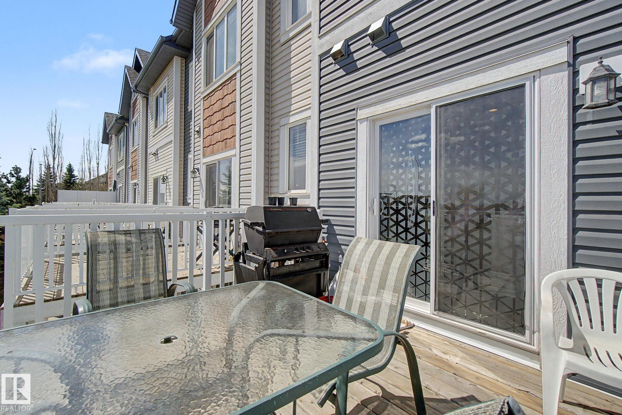 Wood-finish deck with white railings and direct access to the interior via sliding glass doors - 17 320 Secord Boulevard, Edmonton, AB - Outdoor