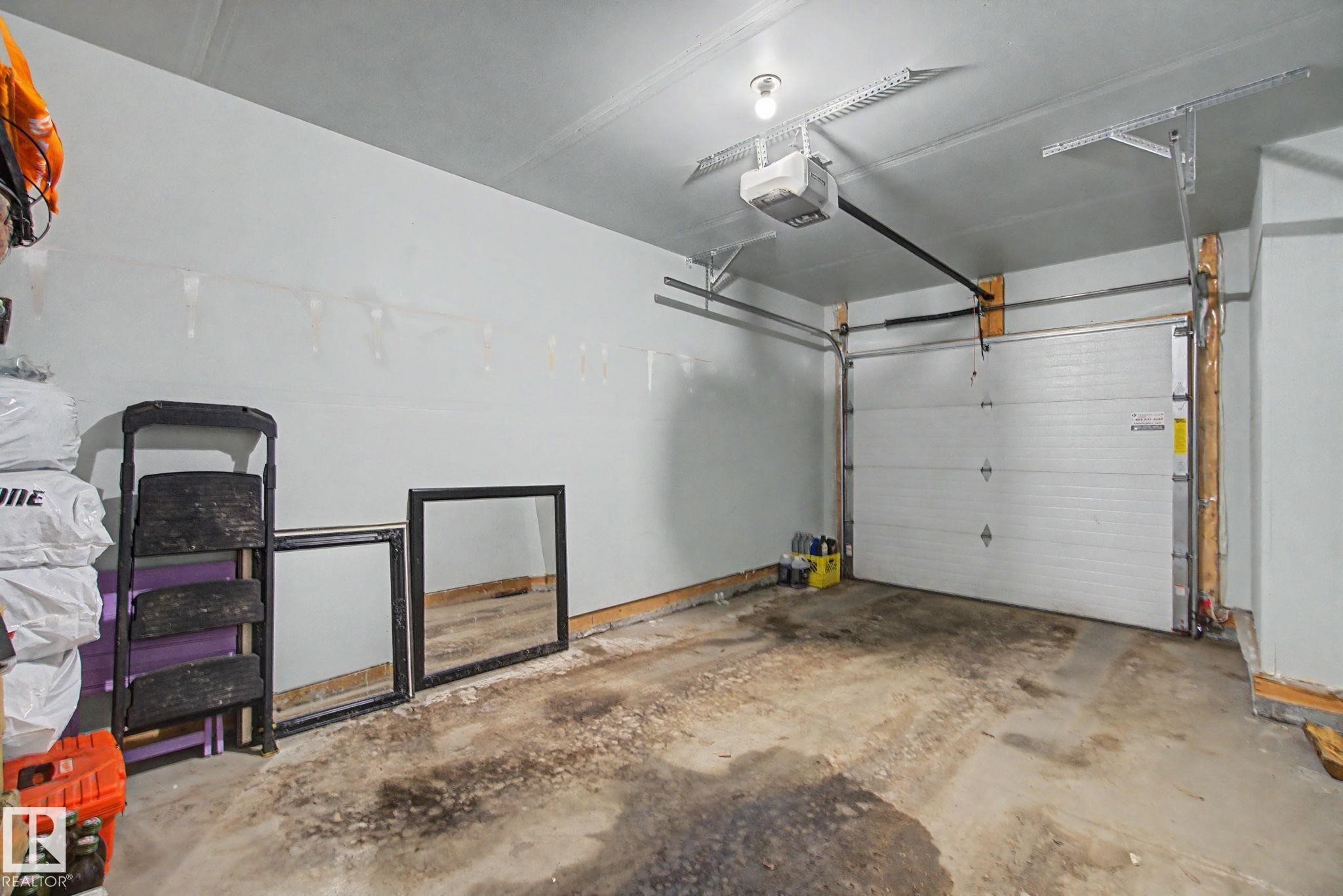 Integrated garage space featuring a white sectional garage door with an automatic opener - 17 320 Secord Boulevard, Edmonton, AB - Indoor Photo Showing Garage