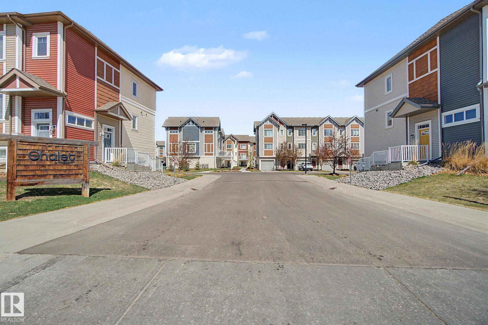 Tree-lined street featuring multi-level townhomes with diverse exterior finishes - 17 320 Secord Boulevard, Edmonton, AB - Outdoor With Facade