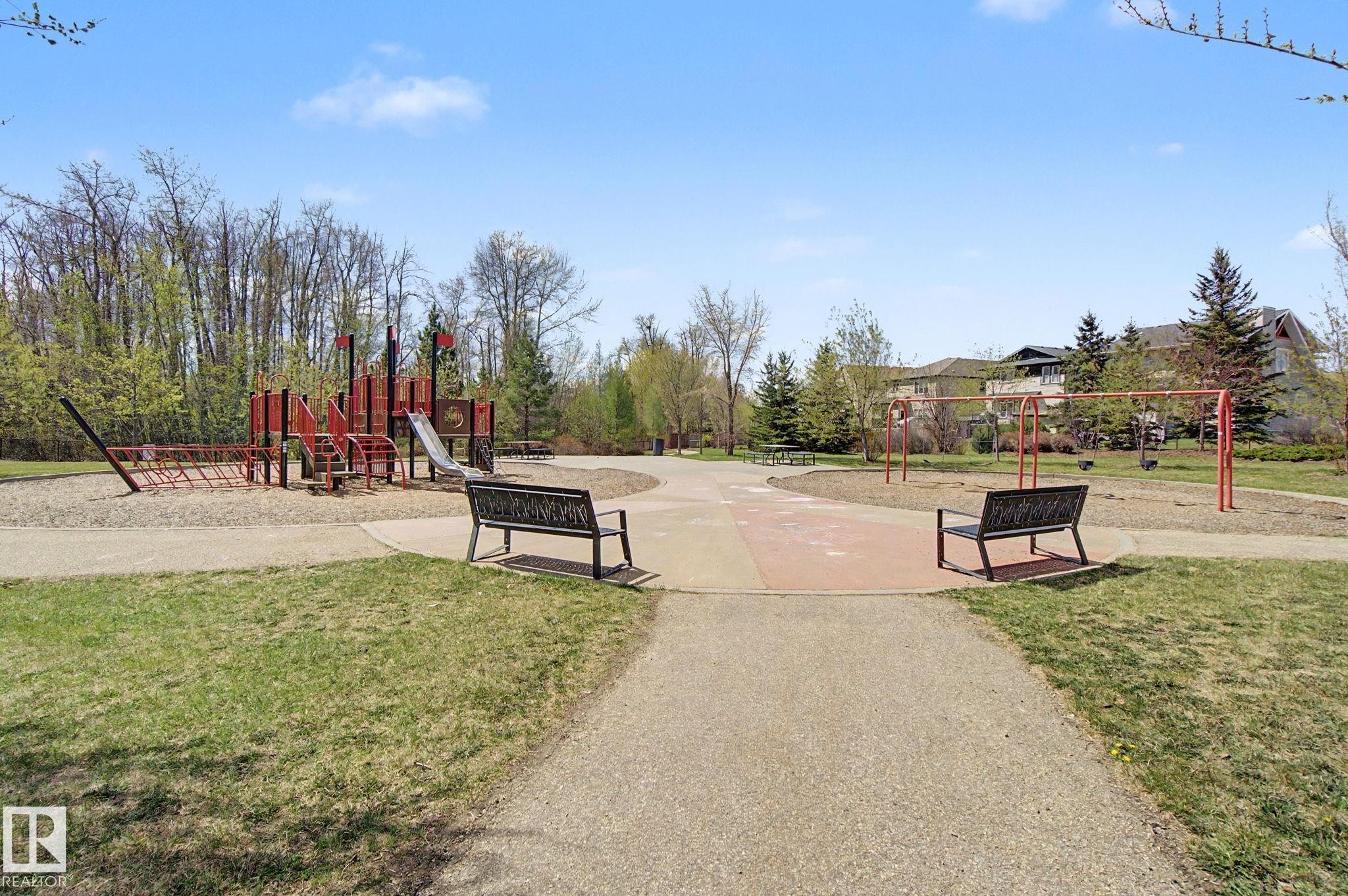 Community park featuring a play structure with slides and climbing elements, a swing set, and integrated park benches - 17 320 Secord Boulevard, Edmonton, AB - Outdoor
