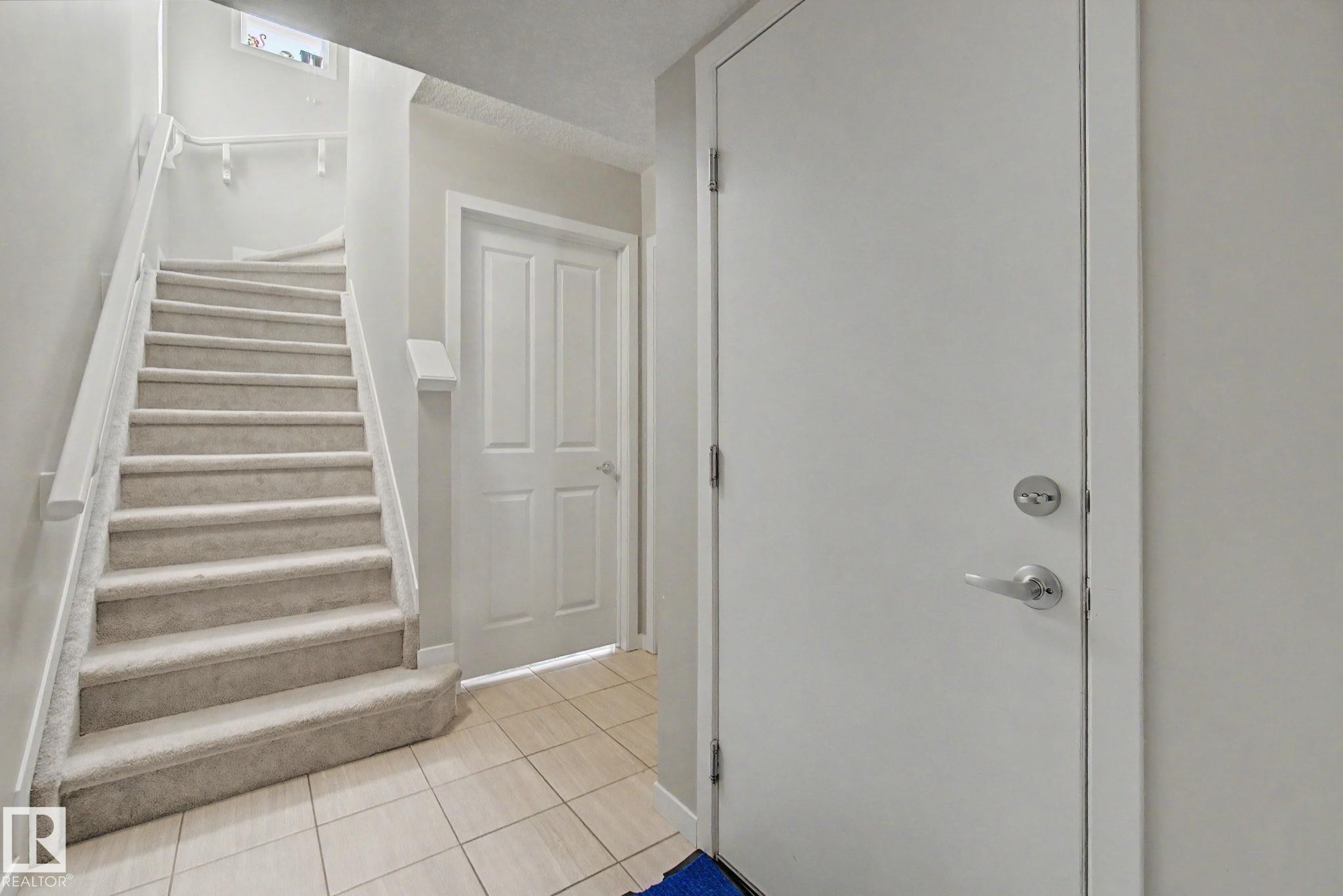 Staircase with light-colored carpeted treads, white handrails, and balusters - 17 320 Secord Boulevard, Edmonton, AB - Indoor Photo Showing Other Room