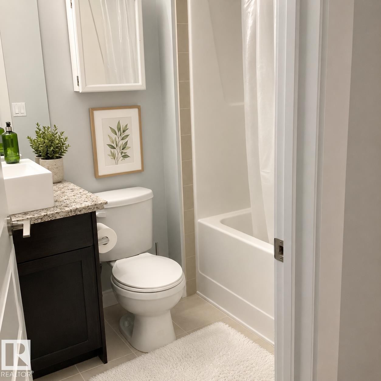 Bathroom featuring a dark wood-finish vanity with a light granite countertop, a rectangular vessel sink, a white toilet, and a white bathtub with a shower unit - 531 5151 Windermere Boulevard, Edmonton, AB - Indoor Photo Showing Bathroom