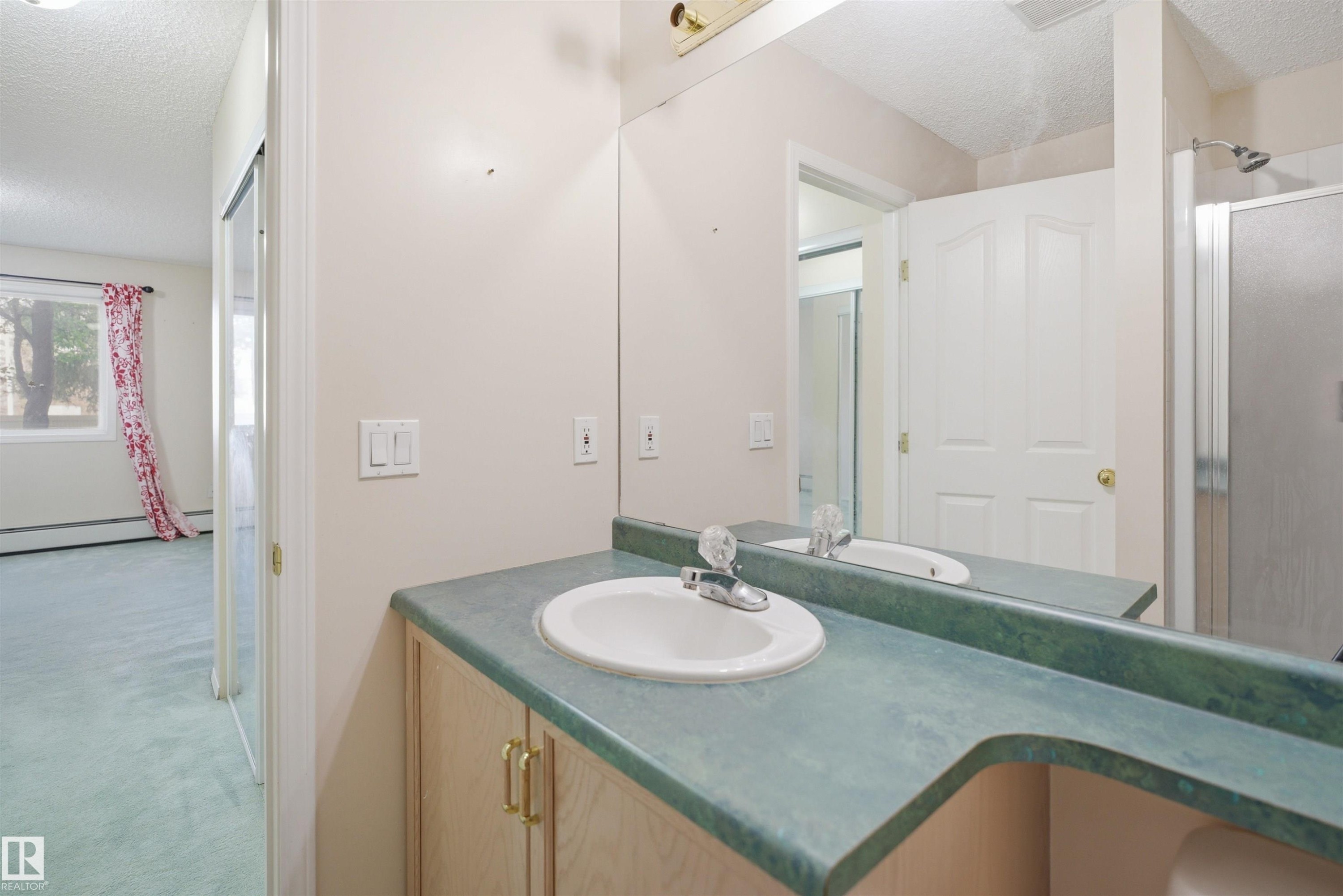 Bathroom vanity featuring an integrated sink, laminate countertop, and wood-finish cabinetry - 124 10511 42 Avenue, Edmonton, AB