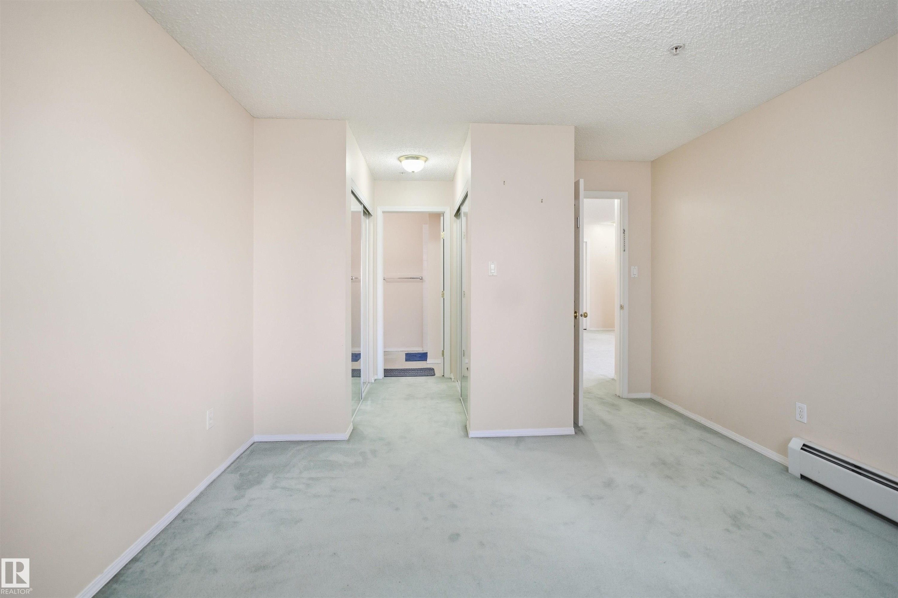 Spacious interior room with light-colored walls and soft green carpeting - 124 10511 42 Avenue, Edmonton, AB