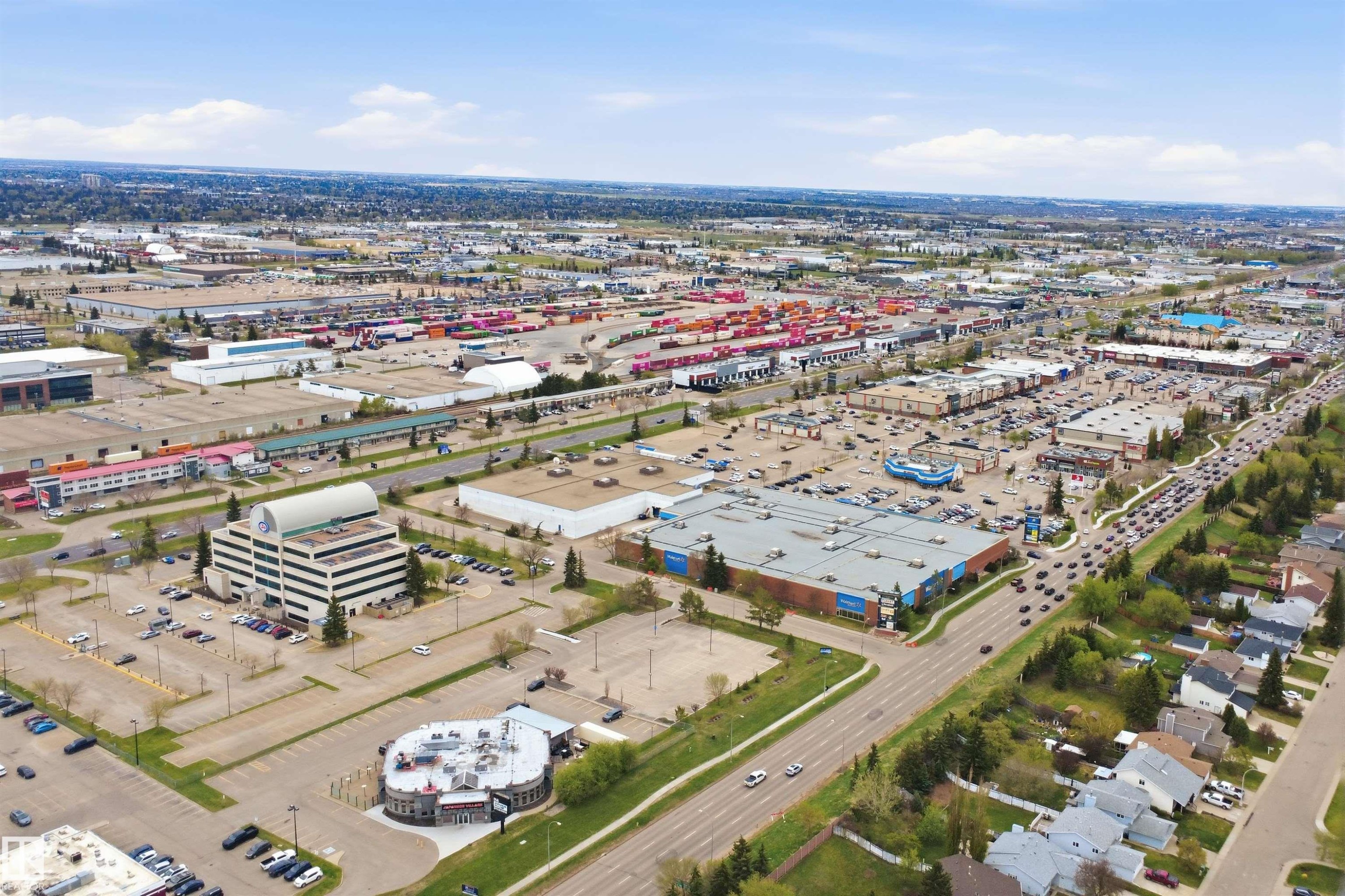 Aerial perspective showcasing a sprawling commercial district with diverse retail and office buildings, expansive parking areas, and mature tree-lined streets - 124 10511 42 Avenue, Edmonton, AB