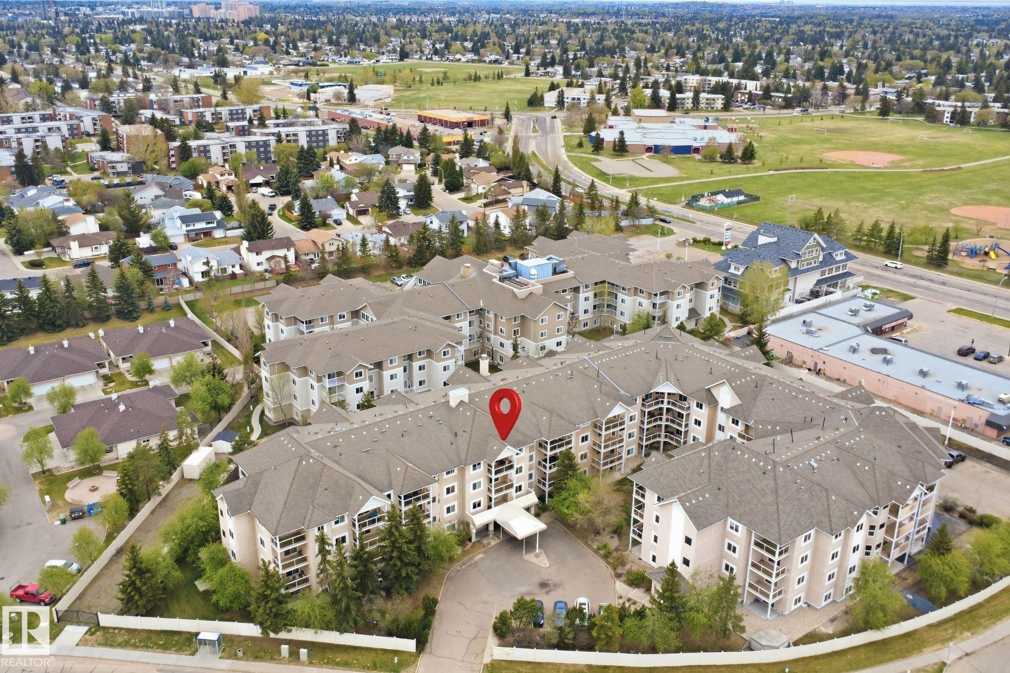 Multi-story residential complex featuring multiple buildings with private balconies and a central entrance canopy - 124 10511 42 Avenue, Edmonton, AB