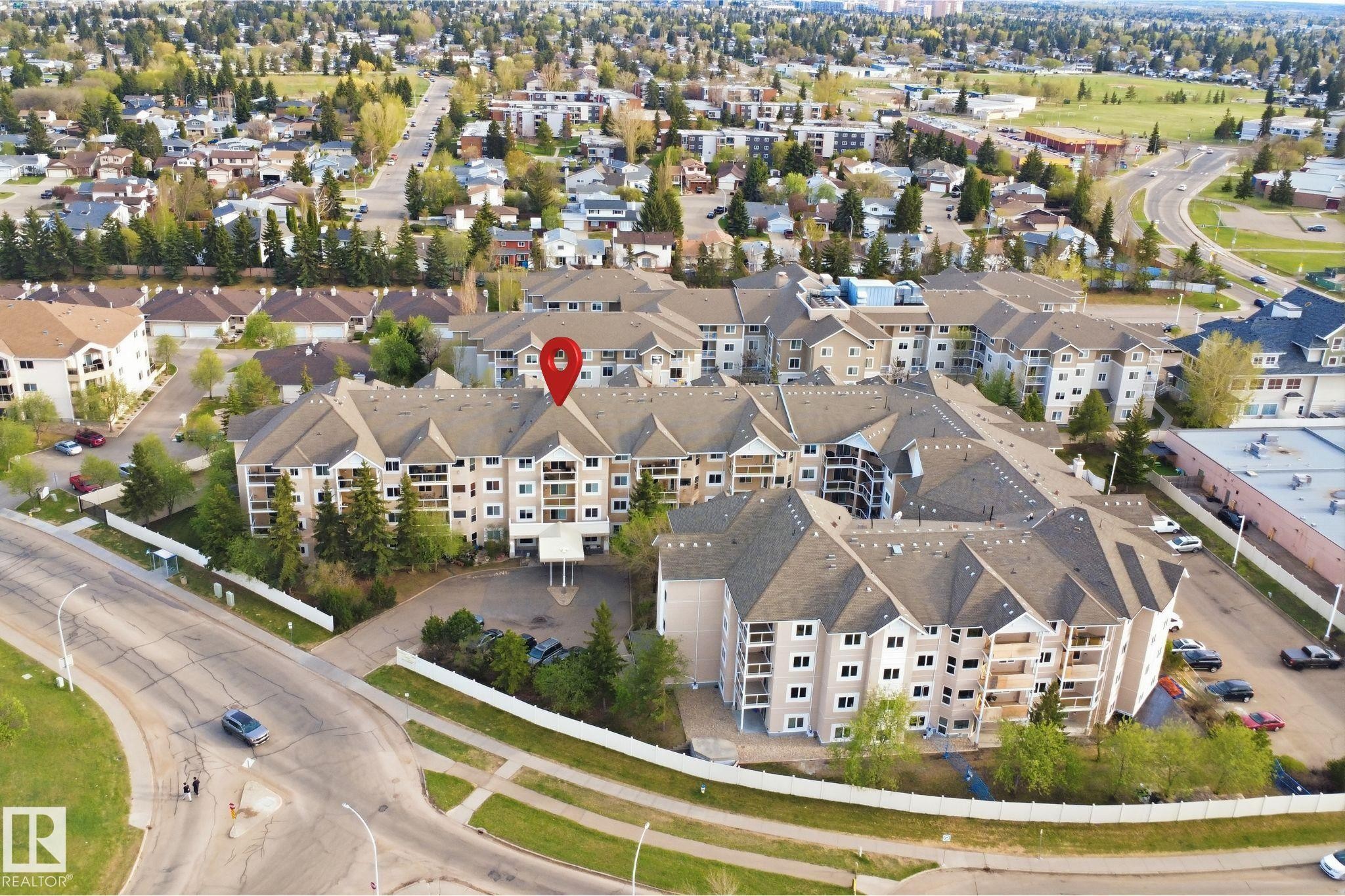 Multi-story condominium complex featuring a light-toned facade, multiple private balconies, and a central covered entrance - 124 10511 42 Avenue, Edmonton, AB