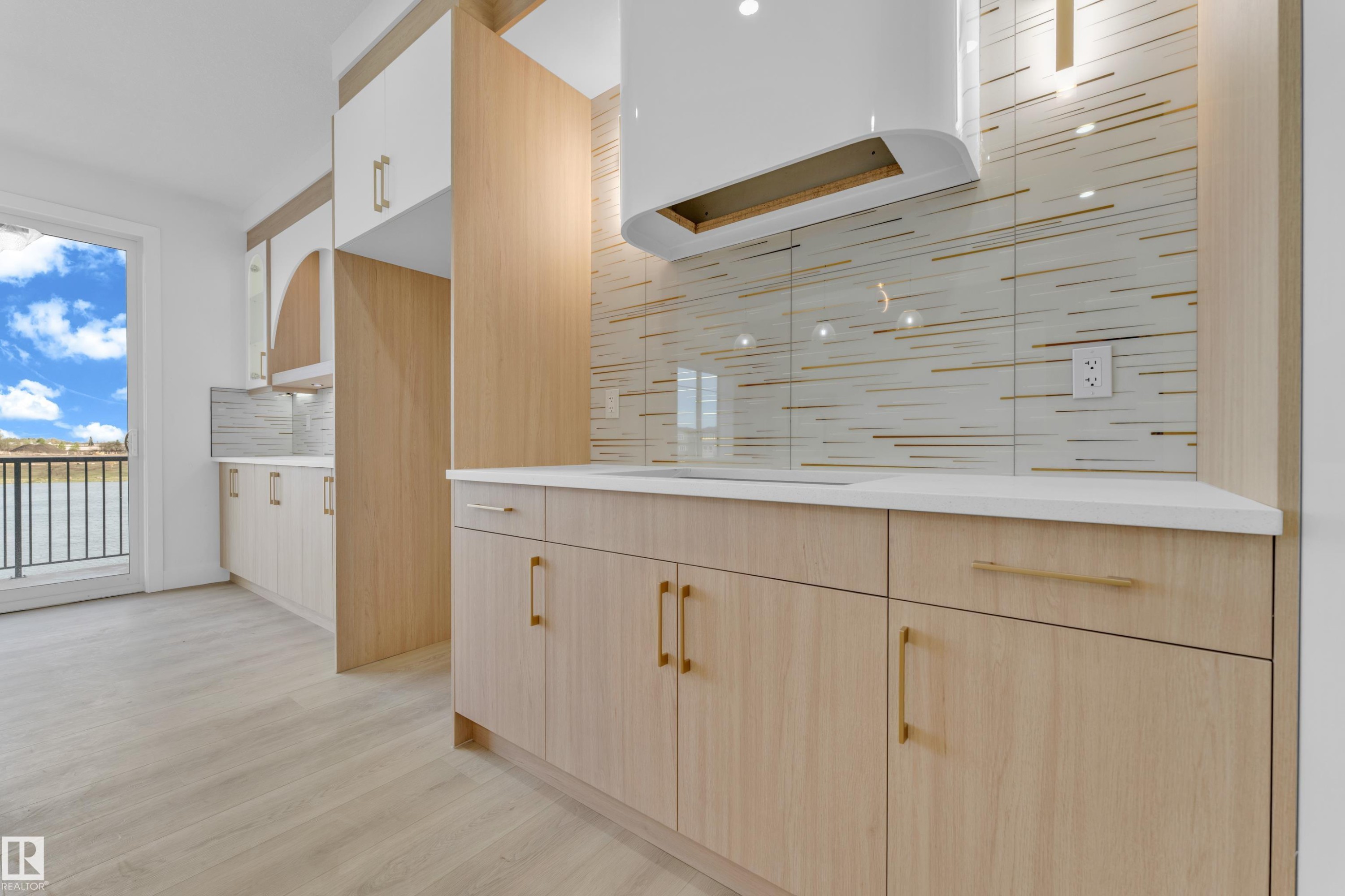 Contemporary kitchen featuring light wood-finish cabinetry with brass-tone hardware, white countertops, and a full-height decorative backsplash - 449 Crystal Creek Link, Leduc, AB - Indoor