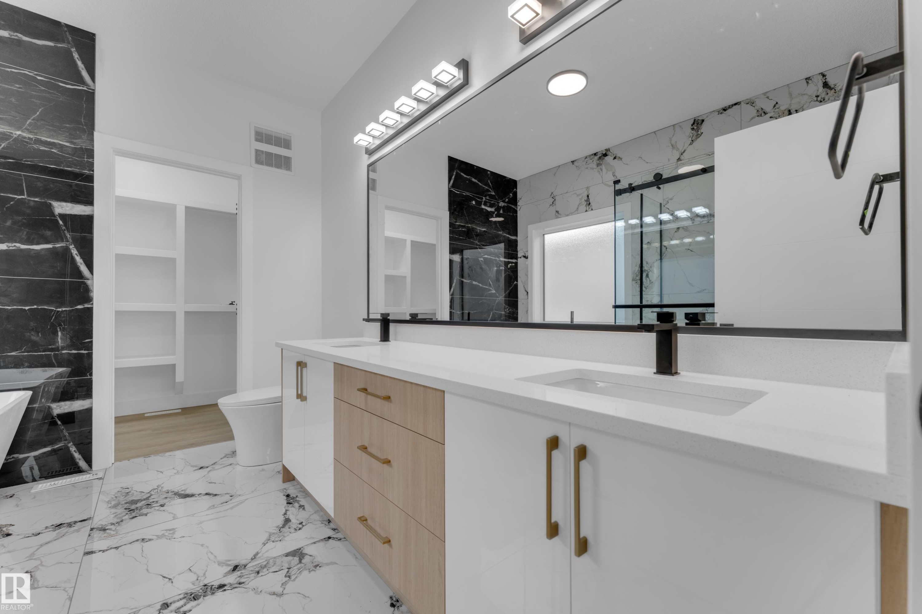 Double vanity featuring two integrated sinks, white countertops, and matte black faucets - 449 Crystal Creek Link, Leduc, AB - Indoor