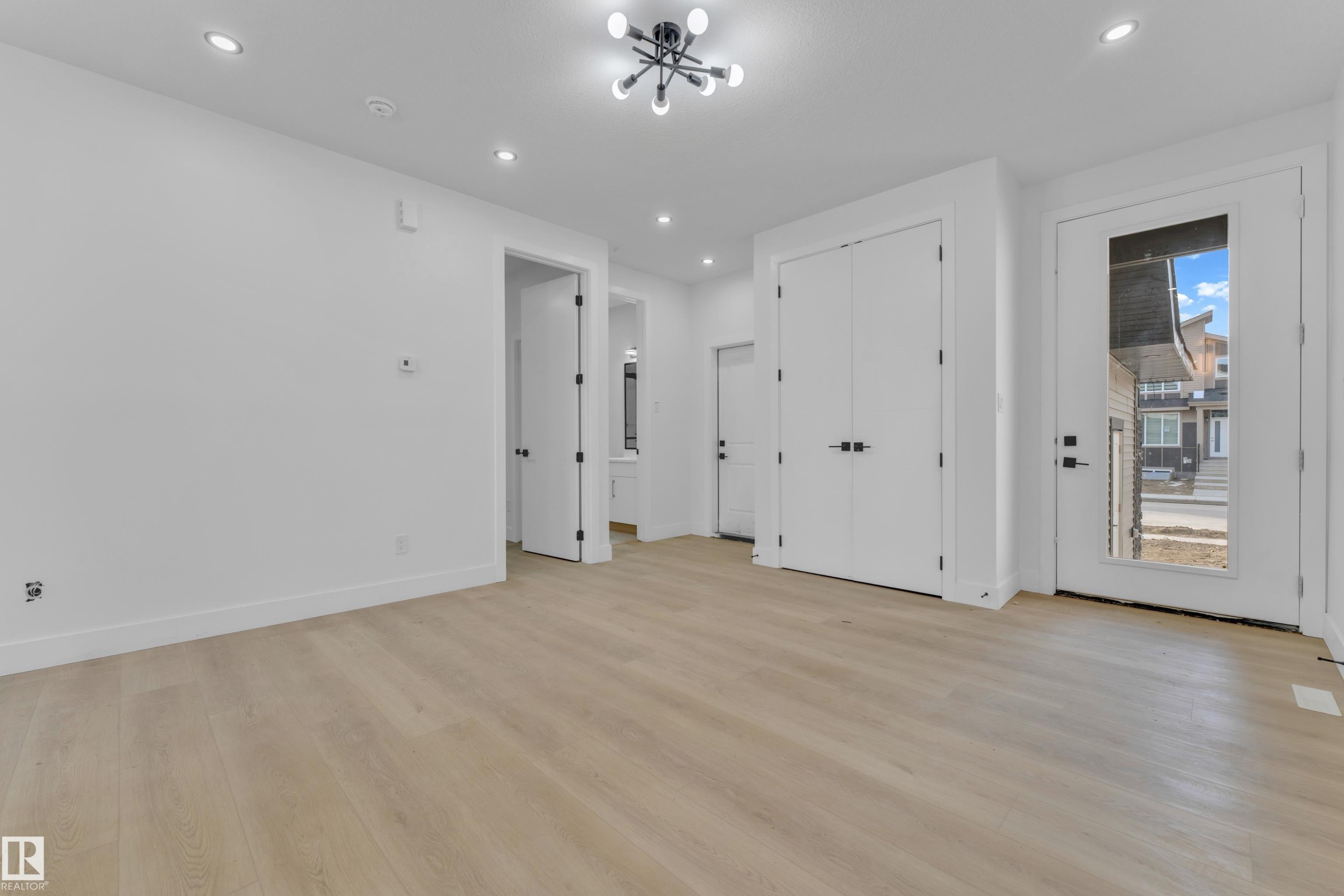 Expansive room featuring wood-finish flooring, recessed lighting, and a modern ceiling fixture - 449 Crystal Creek Link, Leduc, AB - Indoor Photo Showing Other Room