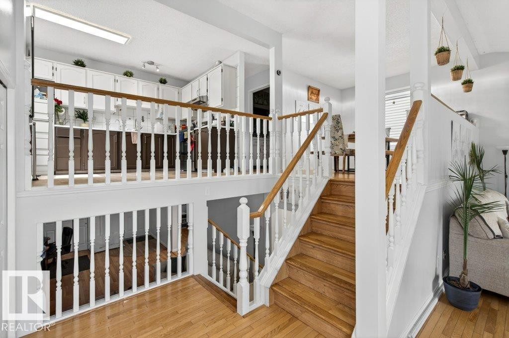 Multilevel interior featuring natural wood stair treads, white balusters, and wood-finish flooring - 157 Kiniski Crescent, Edmonton, AB - Indoor Photo Showing Other Room