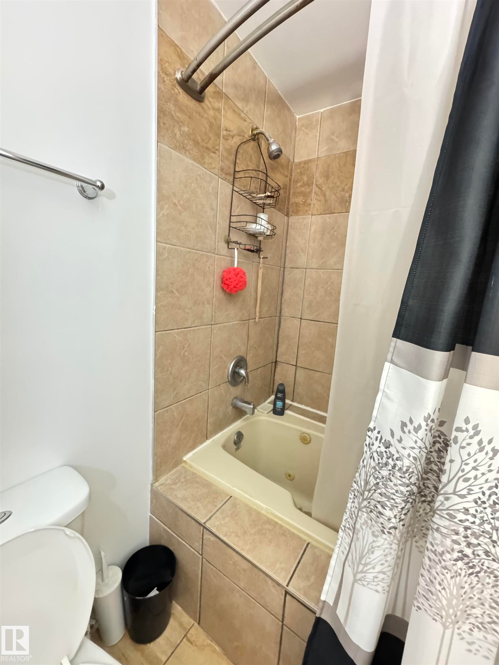 Bathtub with integrated jets surrounded by neutral-toned tiled walls and platform - 45 Lambert Crescent, St. Albert, AB - Indoor Photo Showing Bathroom