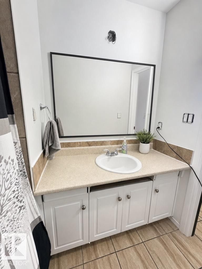 Bathroom vanity featuring white cabinetry with silver-tone hardware, a light-toned countertop, and an integrated oval sink - 45 Lambert Crescent, St. Albert, AB - Indoor Photo Showing Bathroom