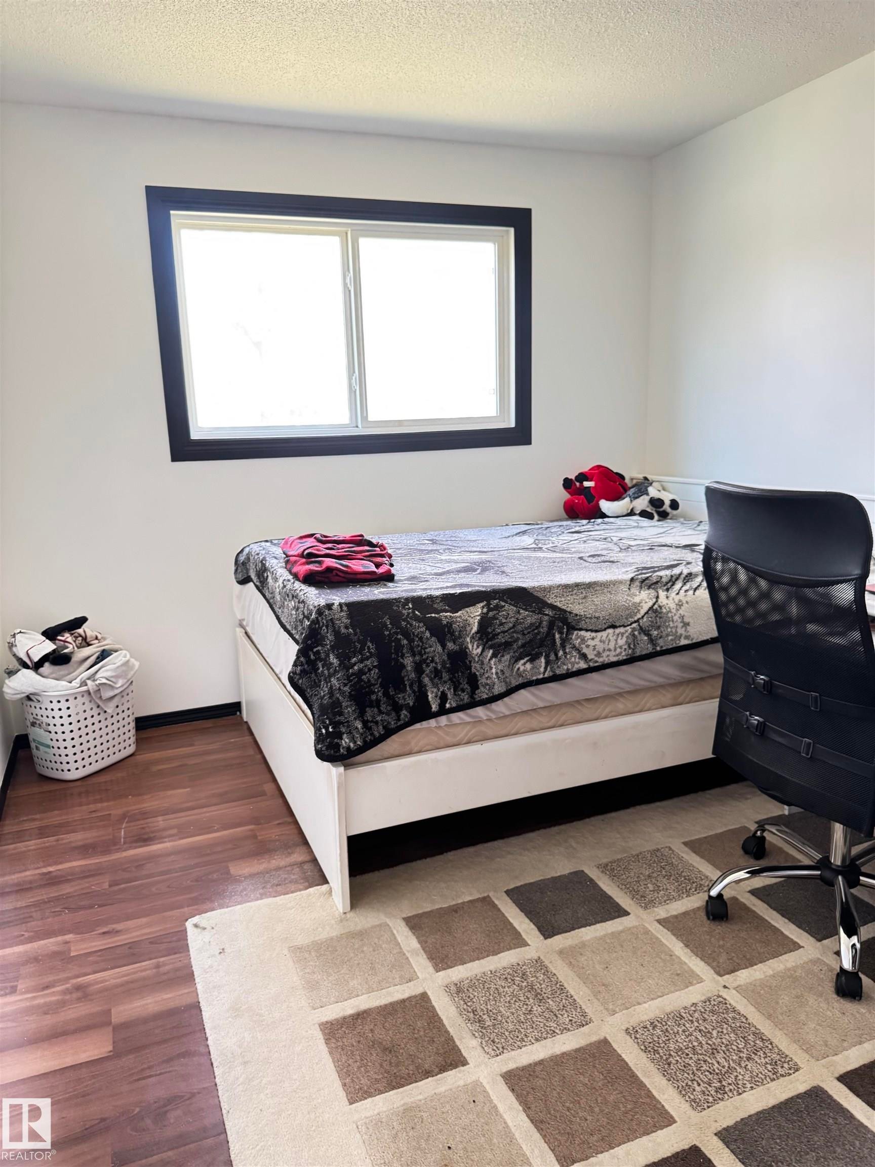 Room featuring wood-finish flooring, a double-pane window with dark trim, and light-colored walls - 45 Lambert Crescent, St. Albert, AB - Indoor Photo Showing Bedroom