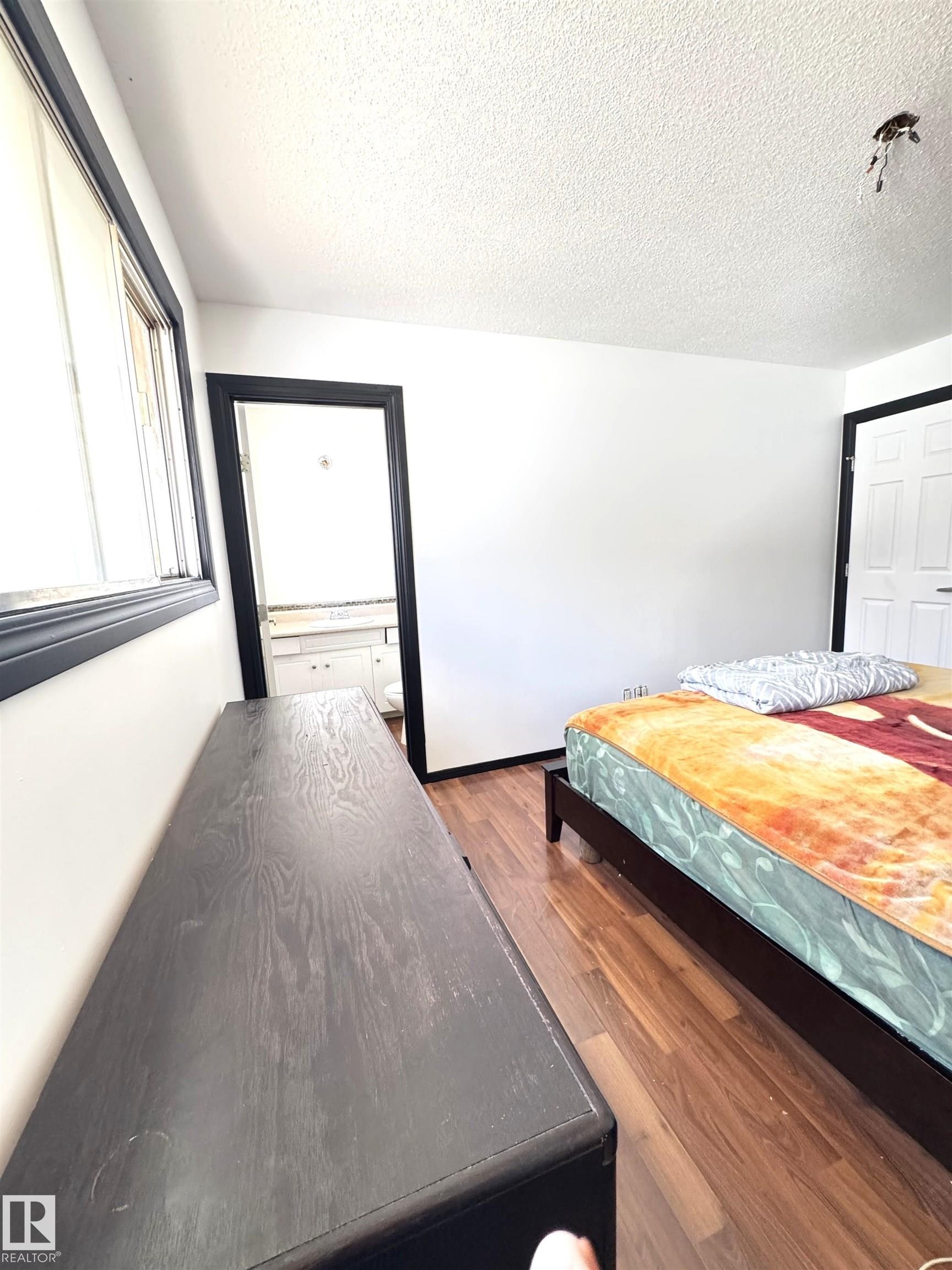 Interior room featuring wood-finish flooring, white walls, and dark trim - 45 Lambert Crescent, St. Albert, AB - Indoor Photo Showing Bedroom