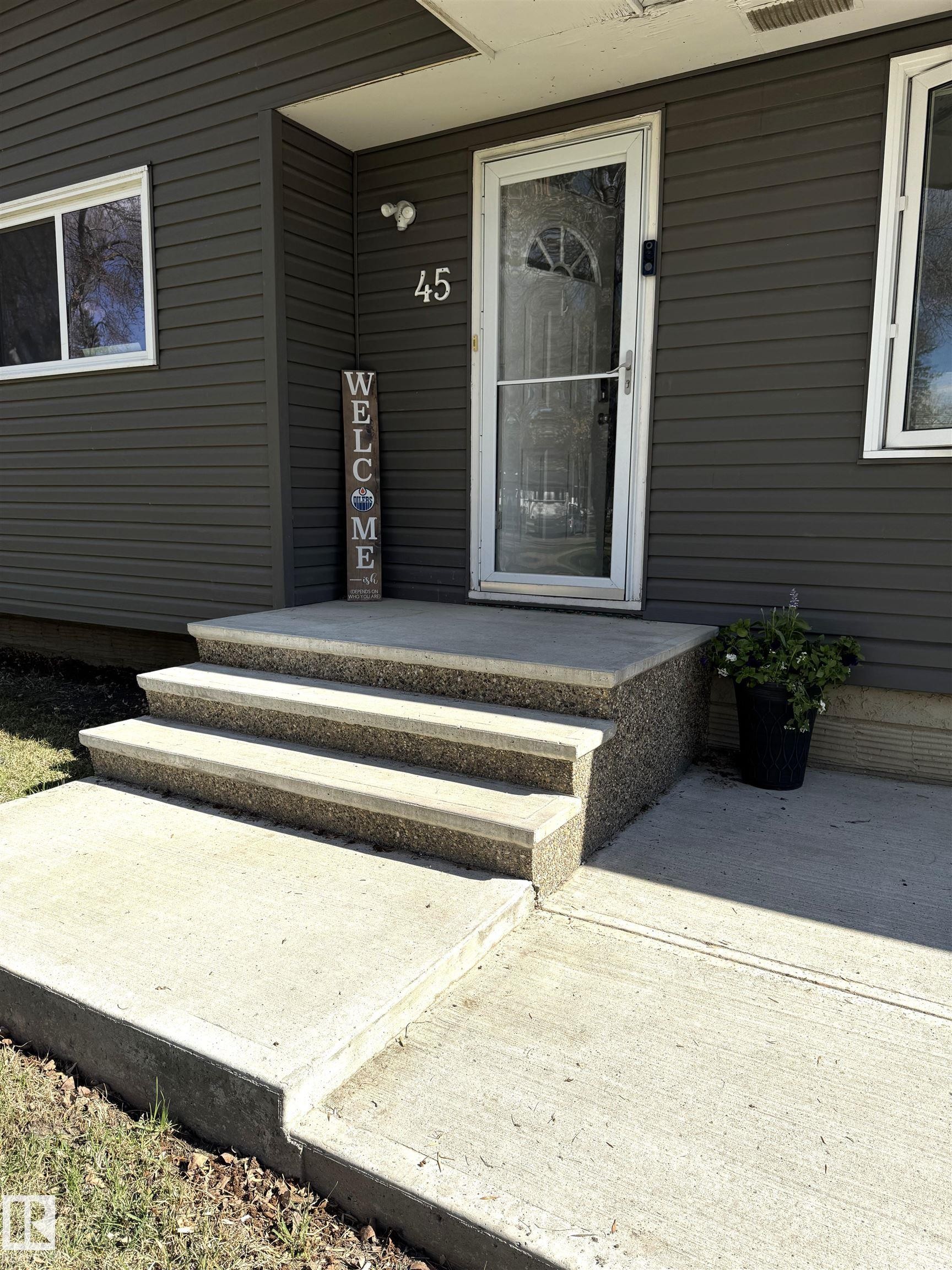Concrete steps and walkway leading to an entryway featuring horizontal siding, white trim, and a storm door - 45 Lambert Crescent, St. Albert, AB - Outdoor With Exterior
