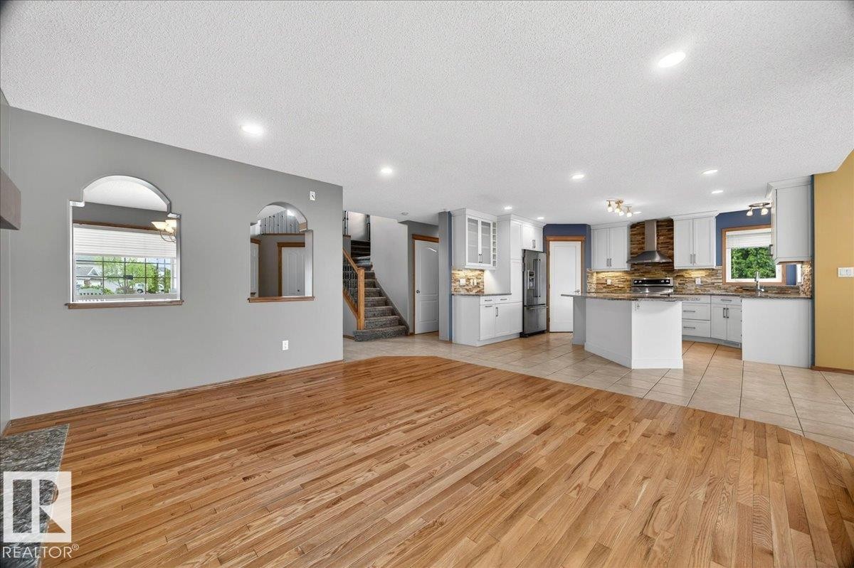 Open-concept living area featuring hardwood flooring, recessed lighting, and a modern kitchen with light cabinetry, stainless steel appliances, and a central island - 11824 13 Avenue, Edmonton, AB - Indoor Photo Showing Kitchen